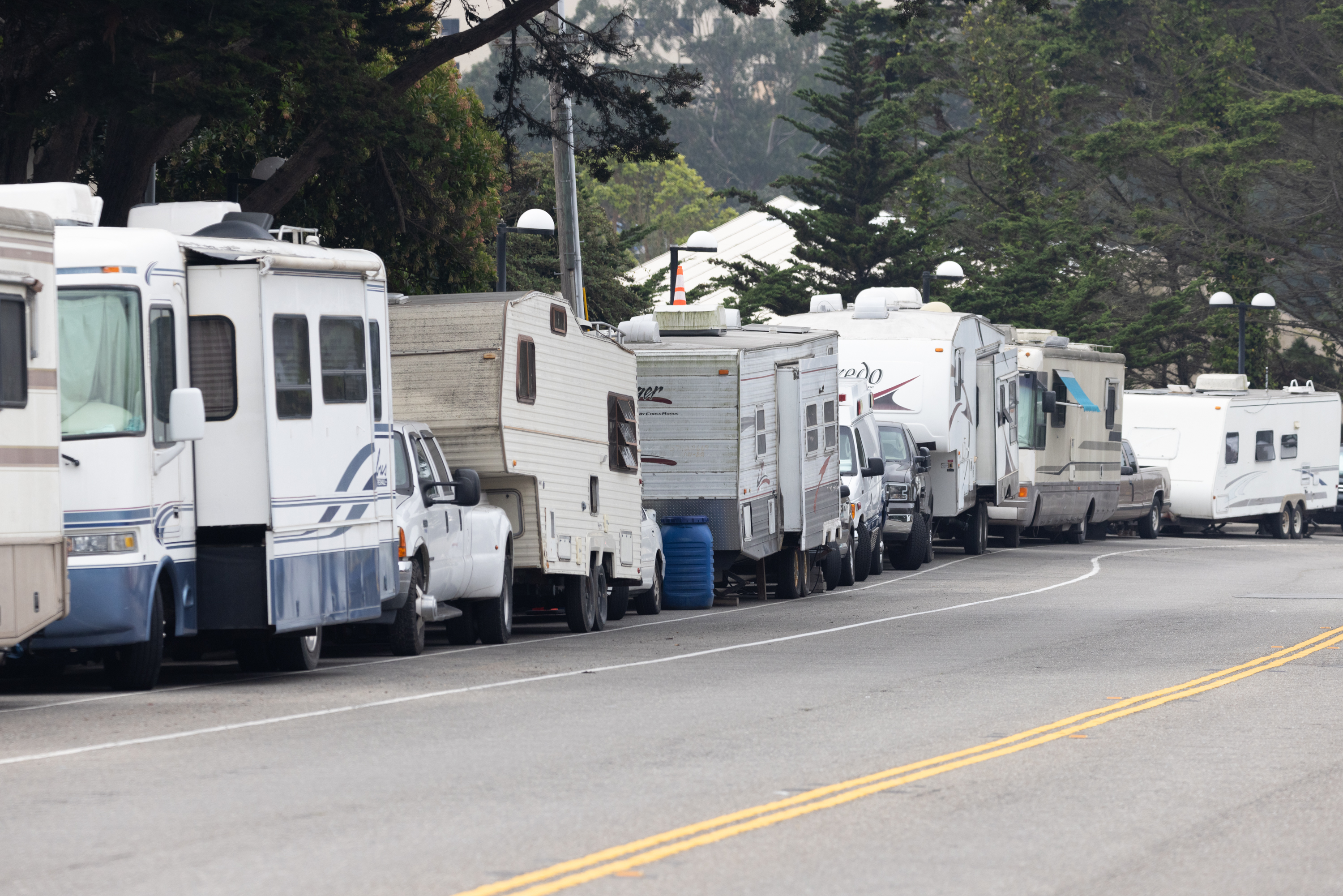 A line of RVs parked on the sidewalk.