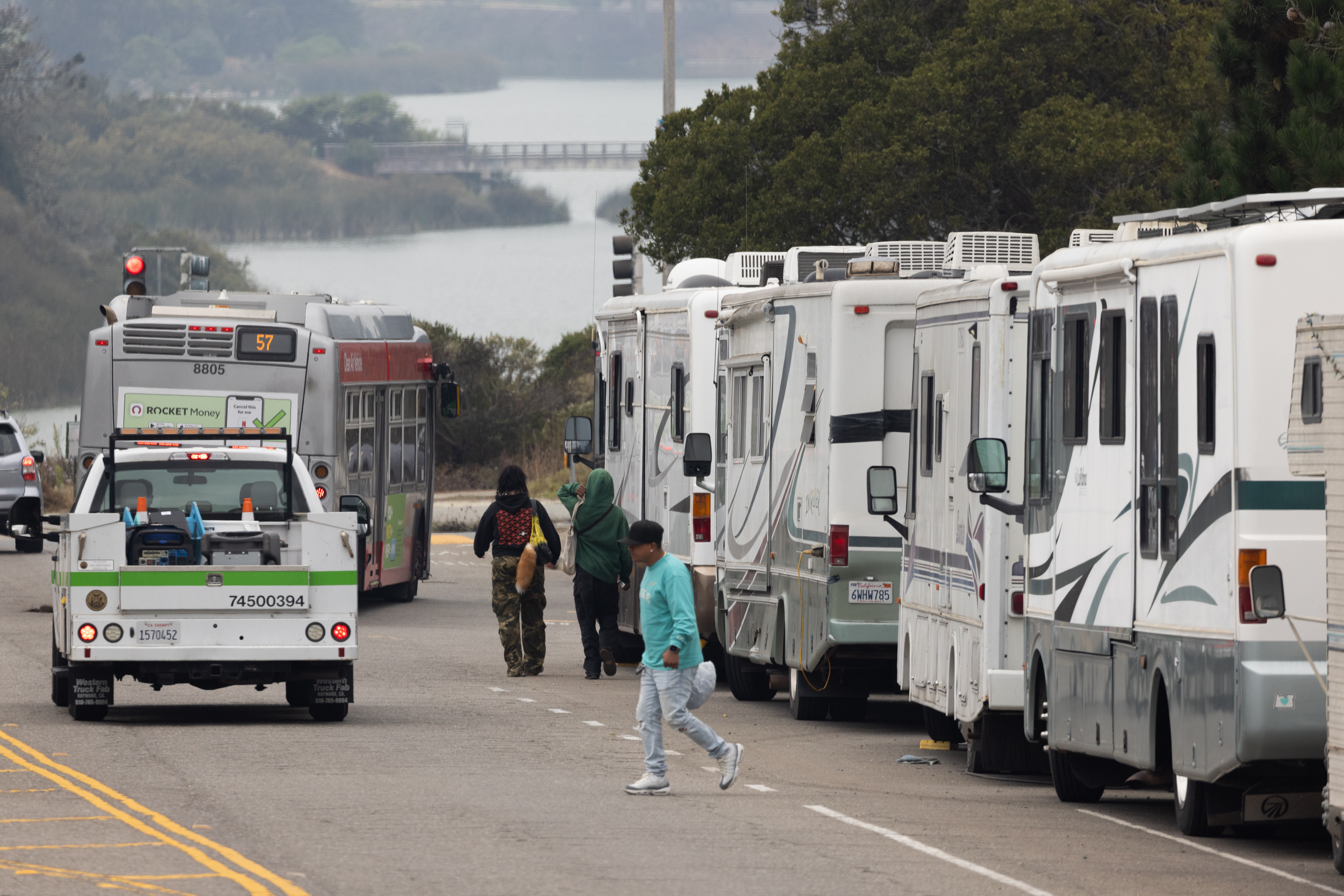 A line of RVs parked as people cross the street.