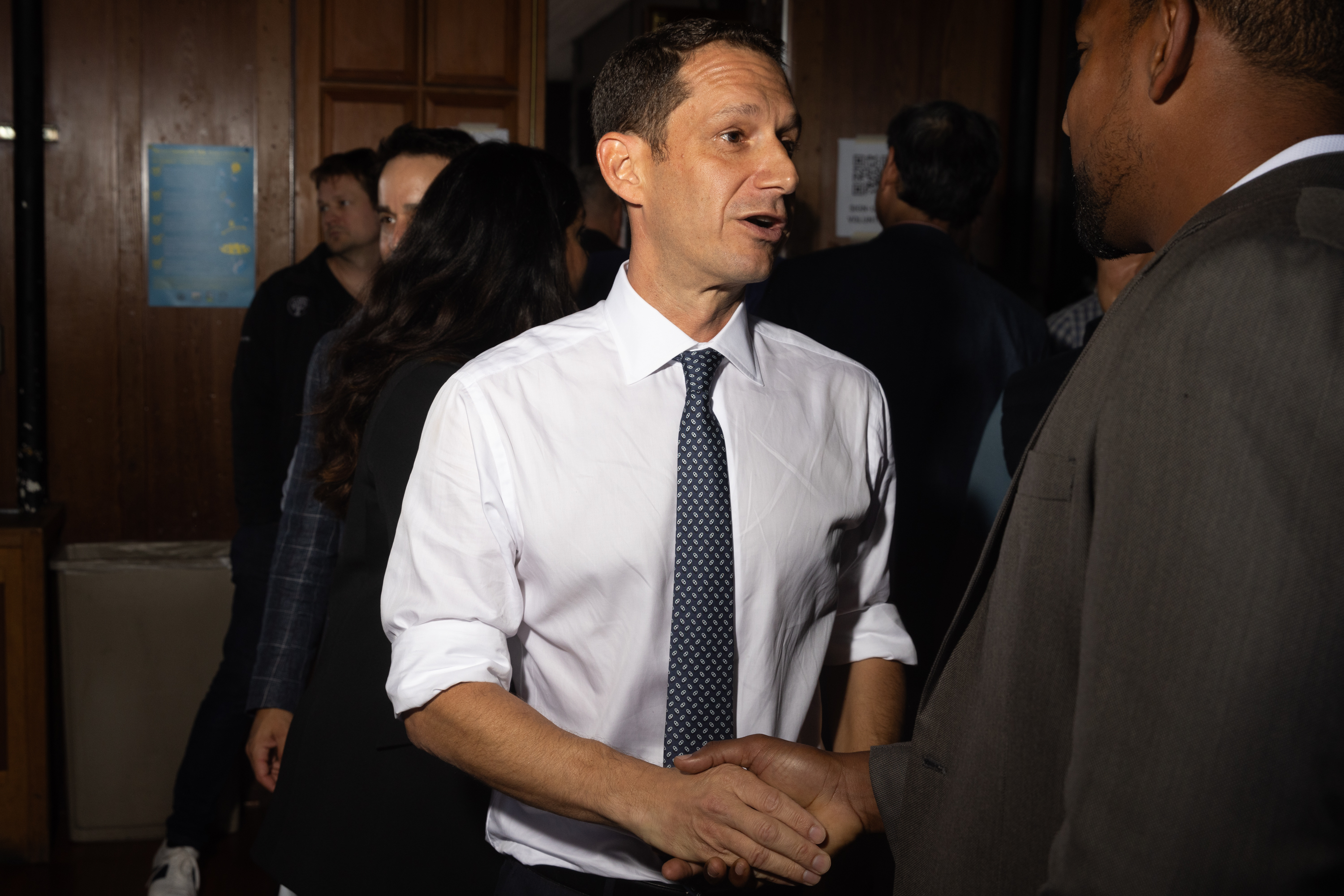 A man in a tie shakes hands with an attendee at a political event. 