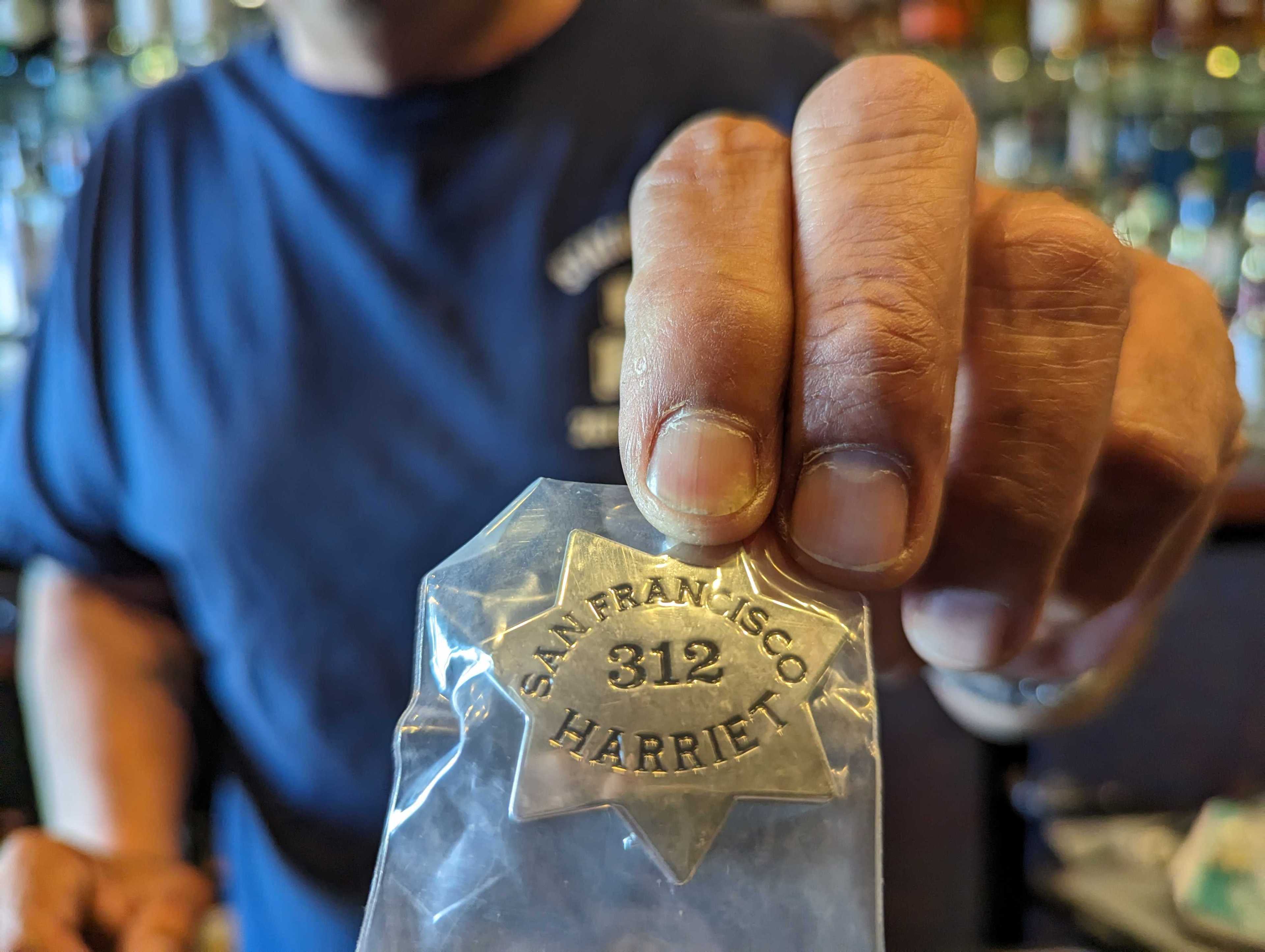 Bar owner Jeffrey Paz shows a pin modeled after a law enforcement badge that features its street address.