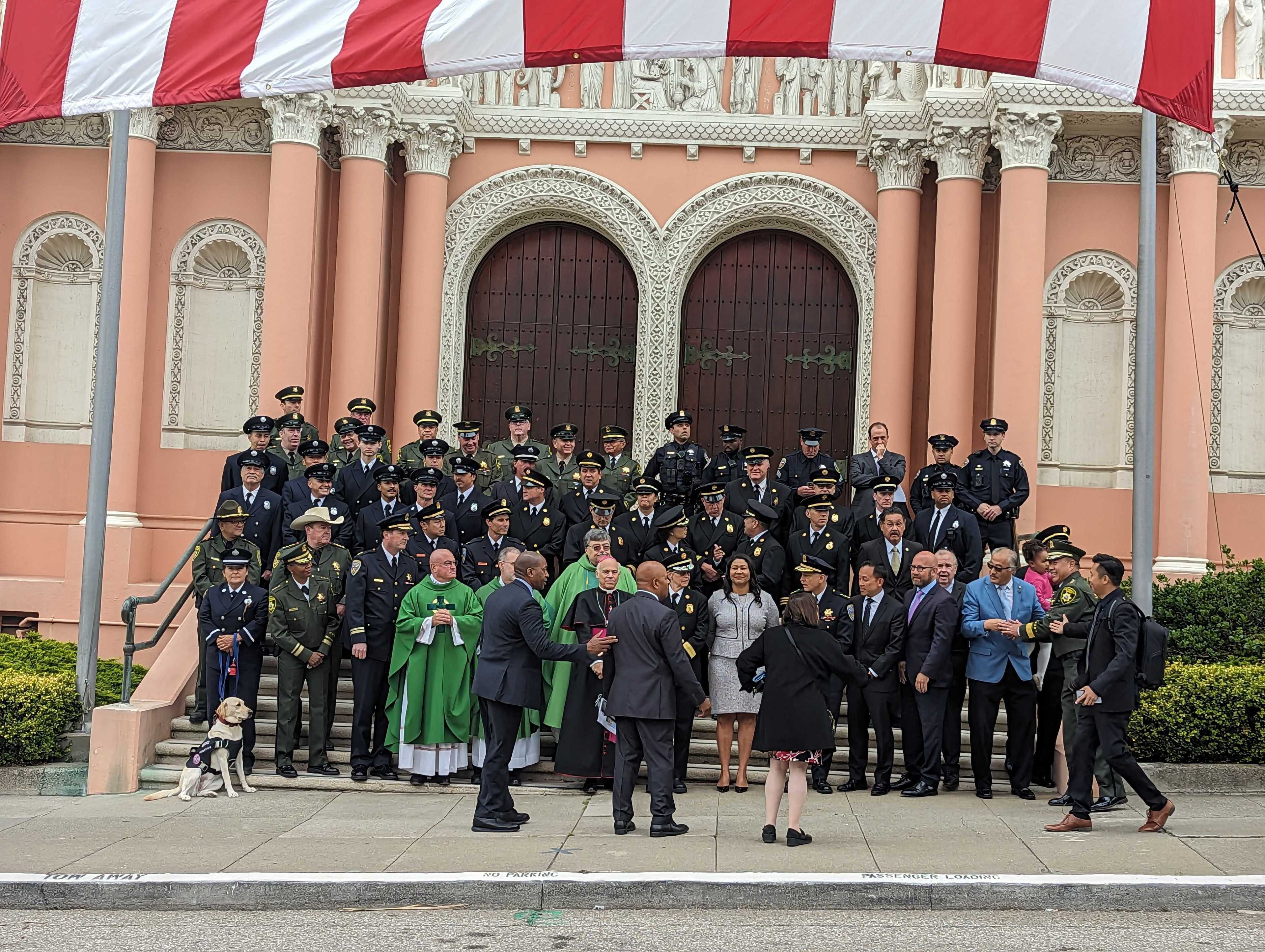 City leaders join police, firefighters and sheriff's deputies under an American flag outside St. Anne of the Sunset Catholic Church, 850 Judah St., before Sunday's 75th annual Police-Fire-Sheriff Memorial Mass.