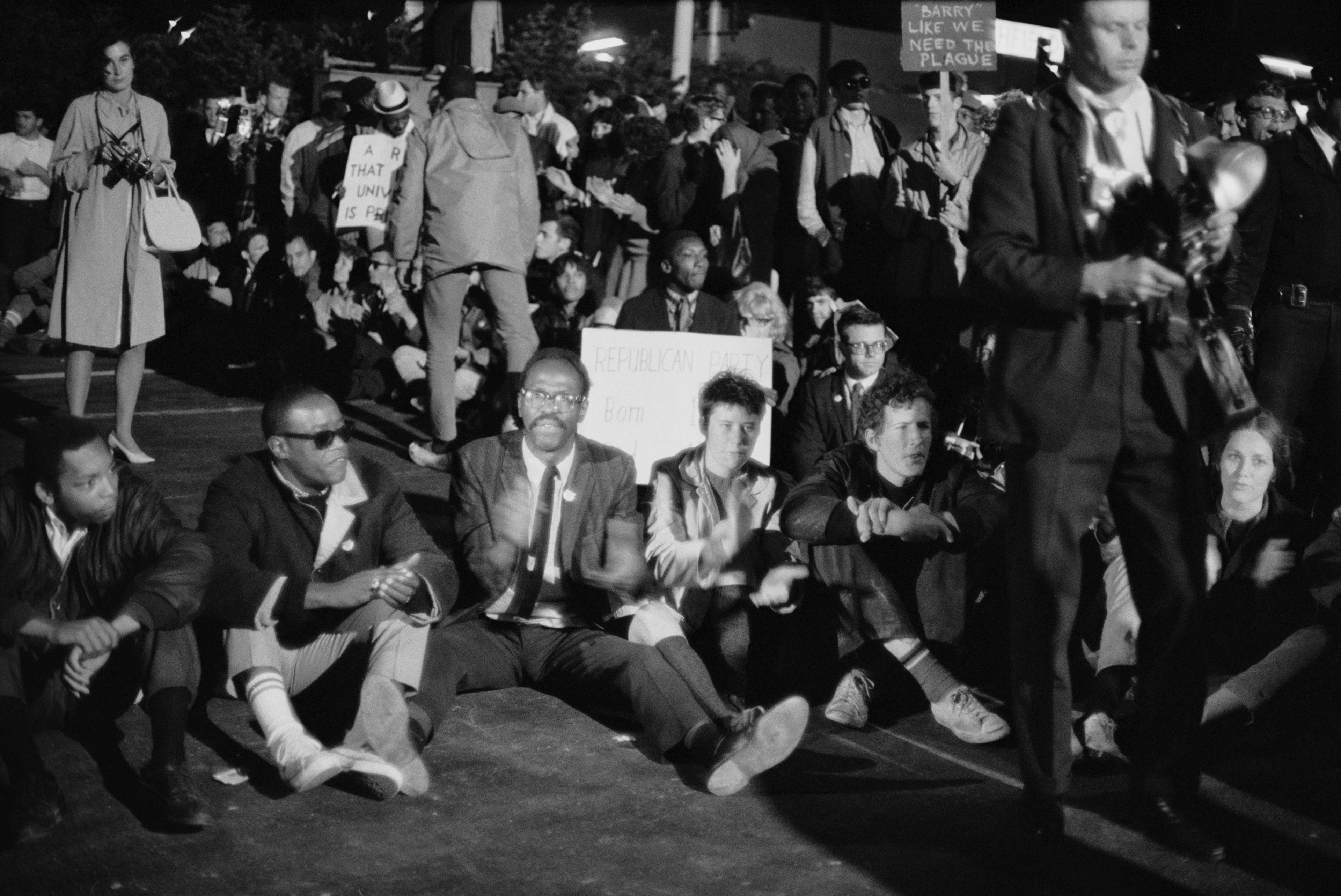 In a black and white photo, protestors gather outside the Republican National Convention at the Cow Palace in Daly City following the nomination of presidential candidate Barry Goldwater.