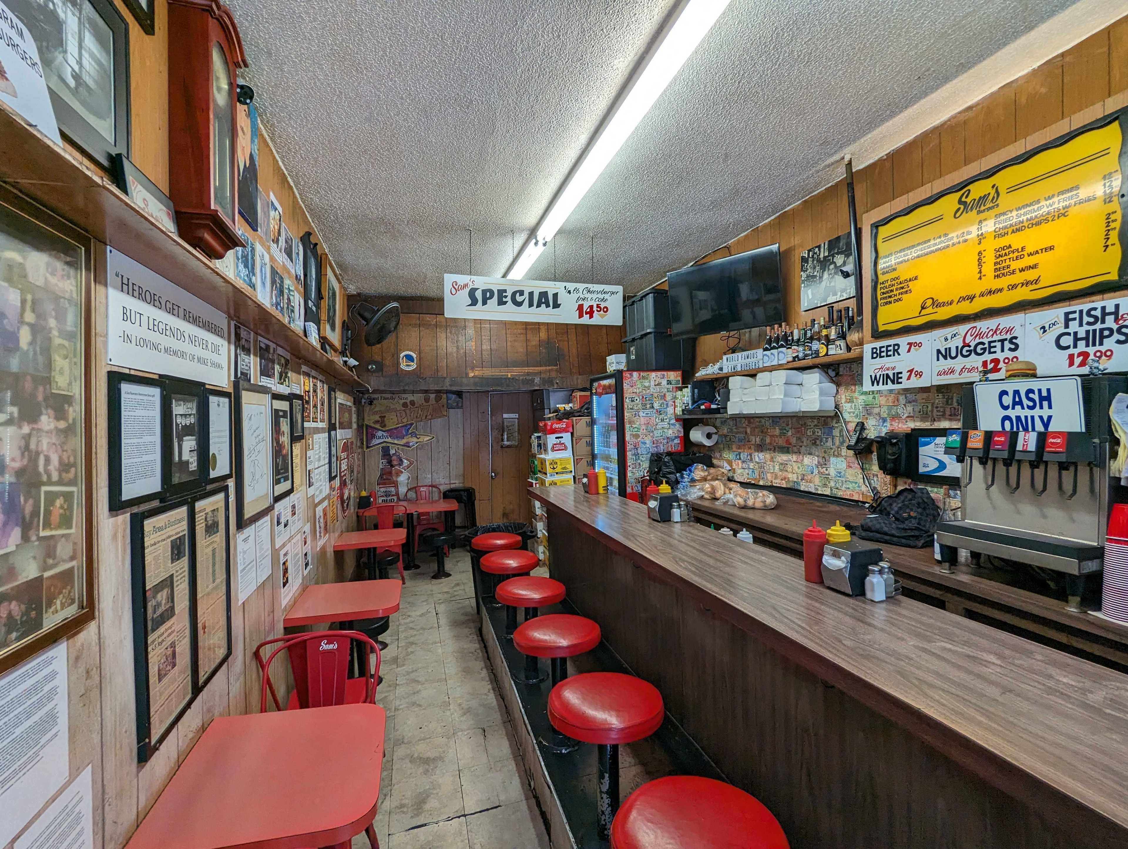 The interior of Sam's Burgers features signs and a long wall lined with old-school menu prices, clippings and memorabilia at its Broadway address in San Francisco's North Beach neighborhood.