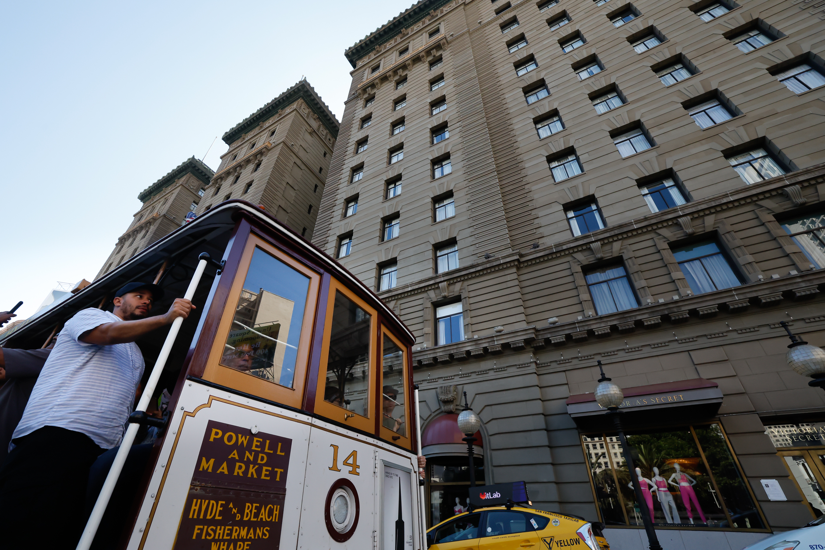 A historic Muni cable car rides by a building