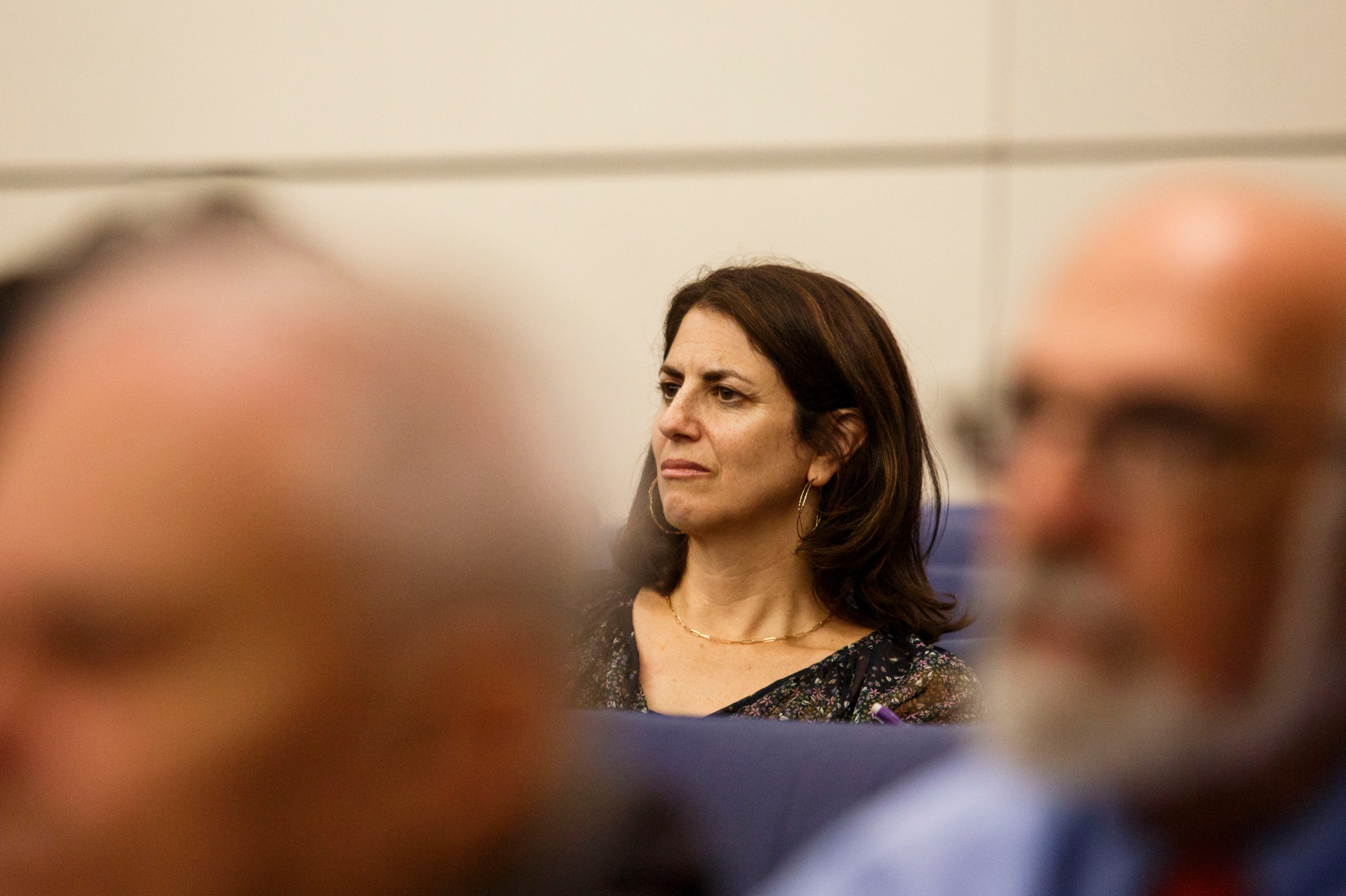 A woman stairs into the distance at a hearing.