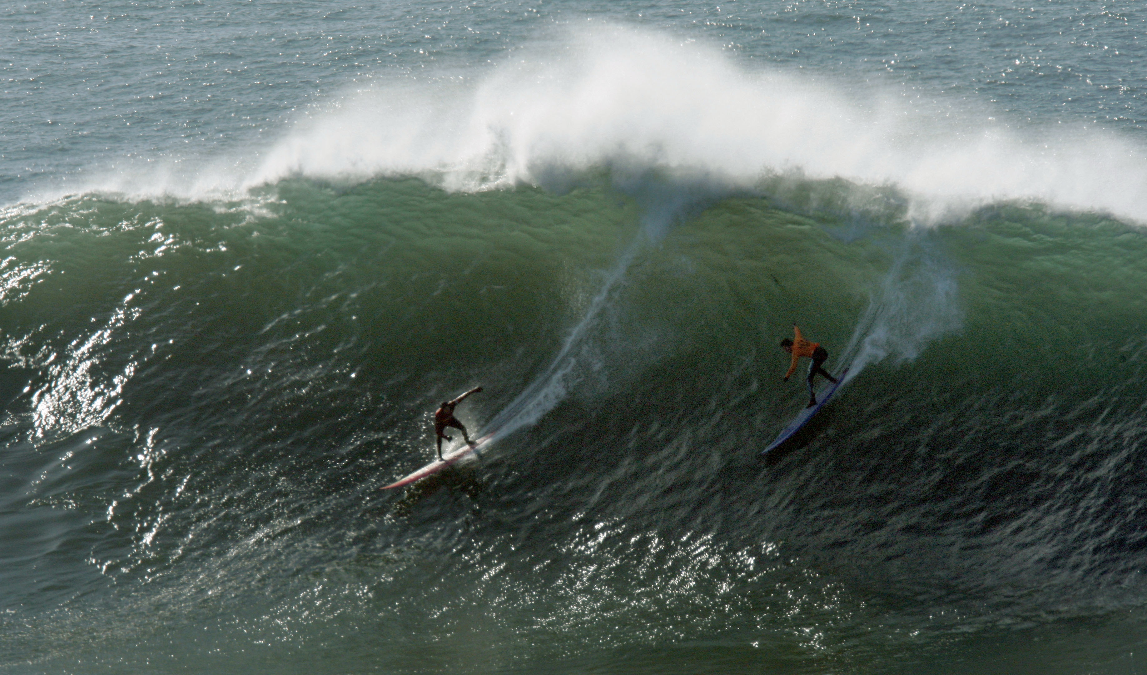 Two surfers ride big wave