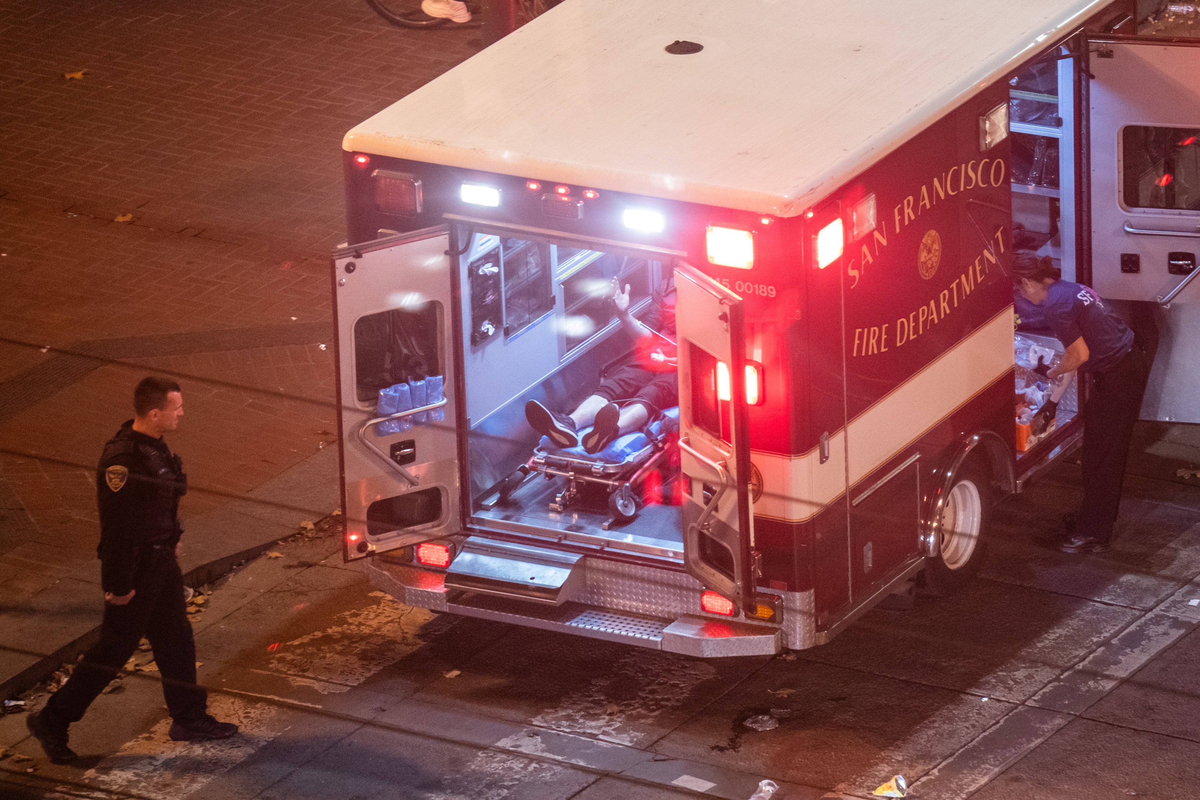 A person lies in an ambulance. Their face is out of frame.