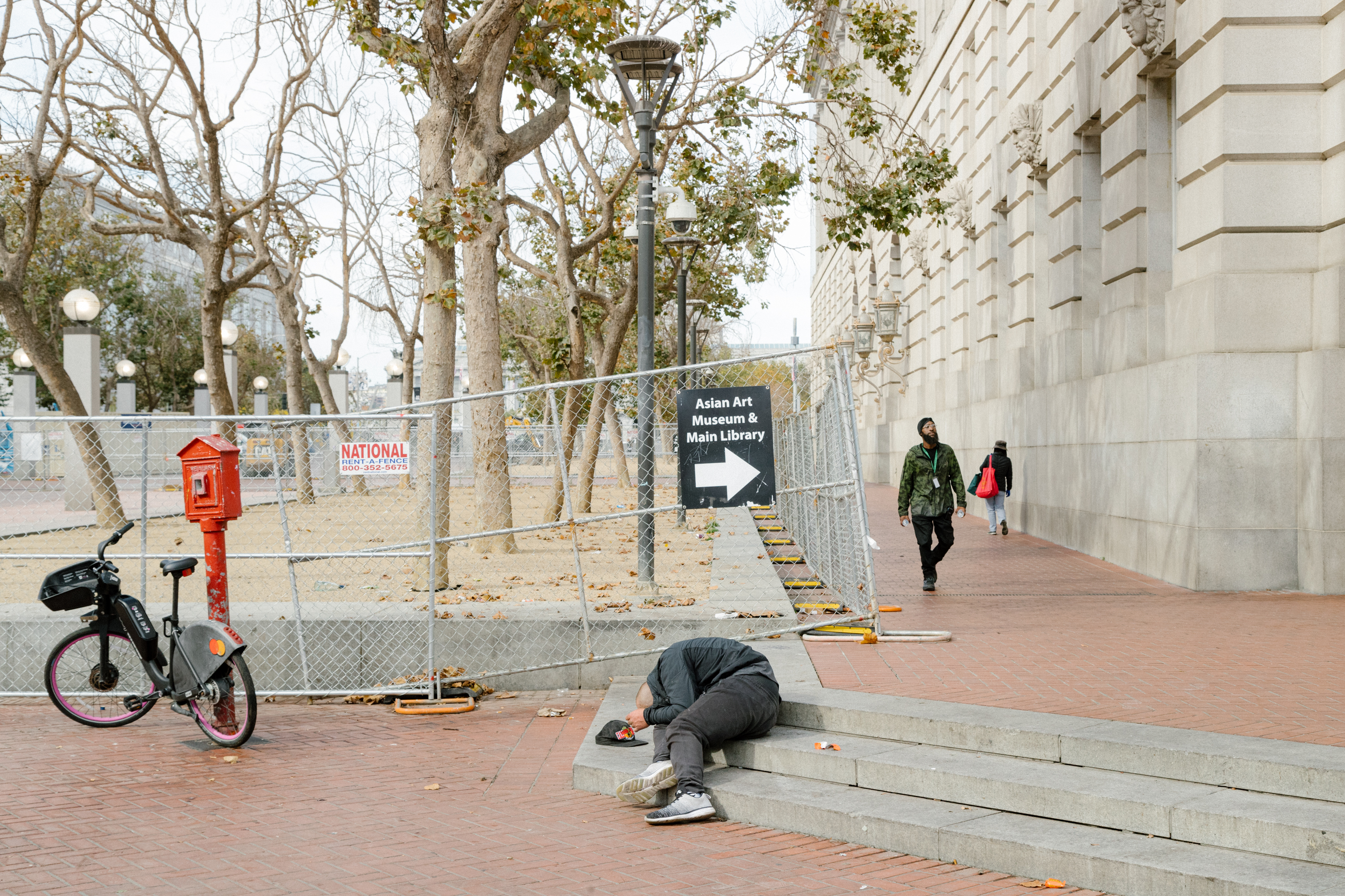 A man hunched over on the steps in UN Plaza in San Francisco on October 13, 2023.