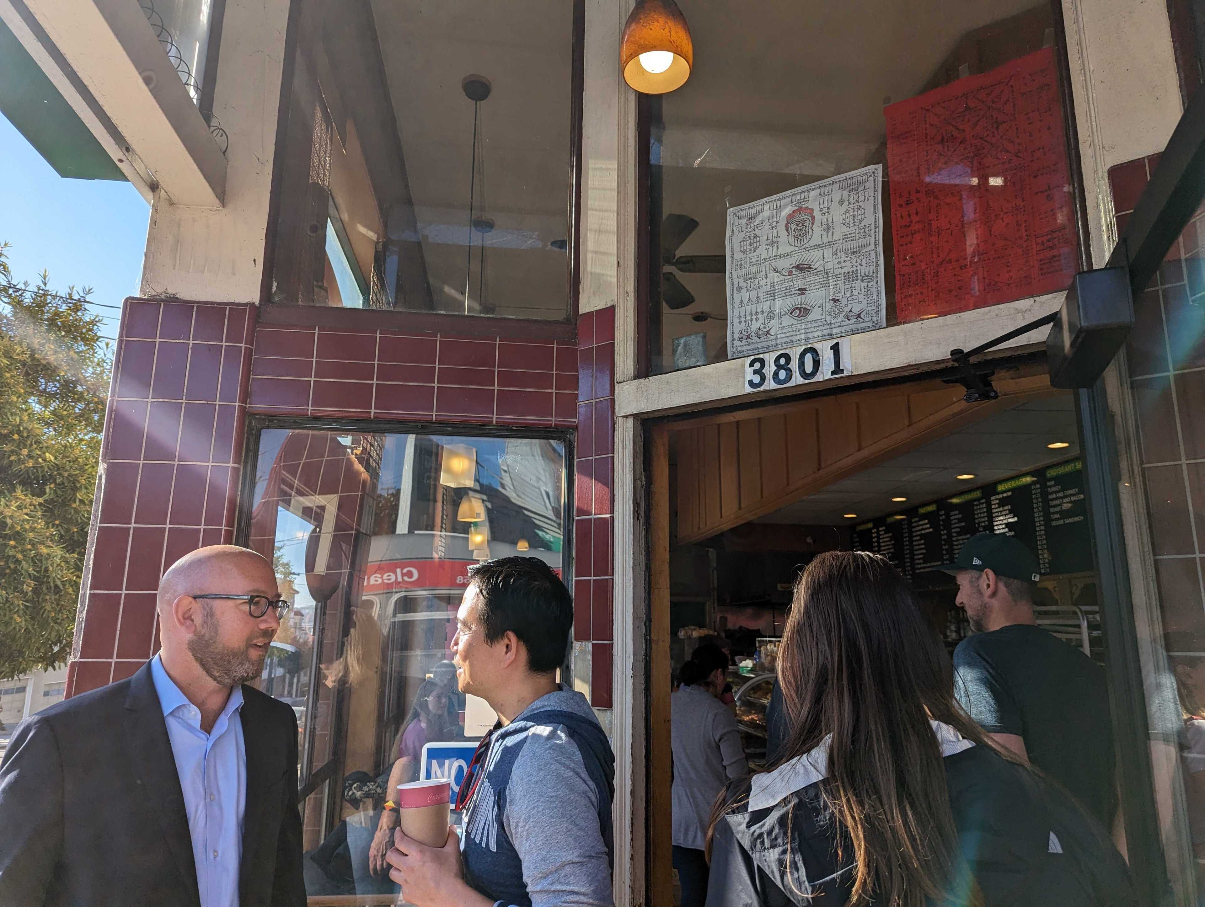San Francisco Supervisor Rafael Mandelman speaks with a district resident Wednesday as a line to enter forms outside Happy Donuts in Noe Valley.