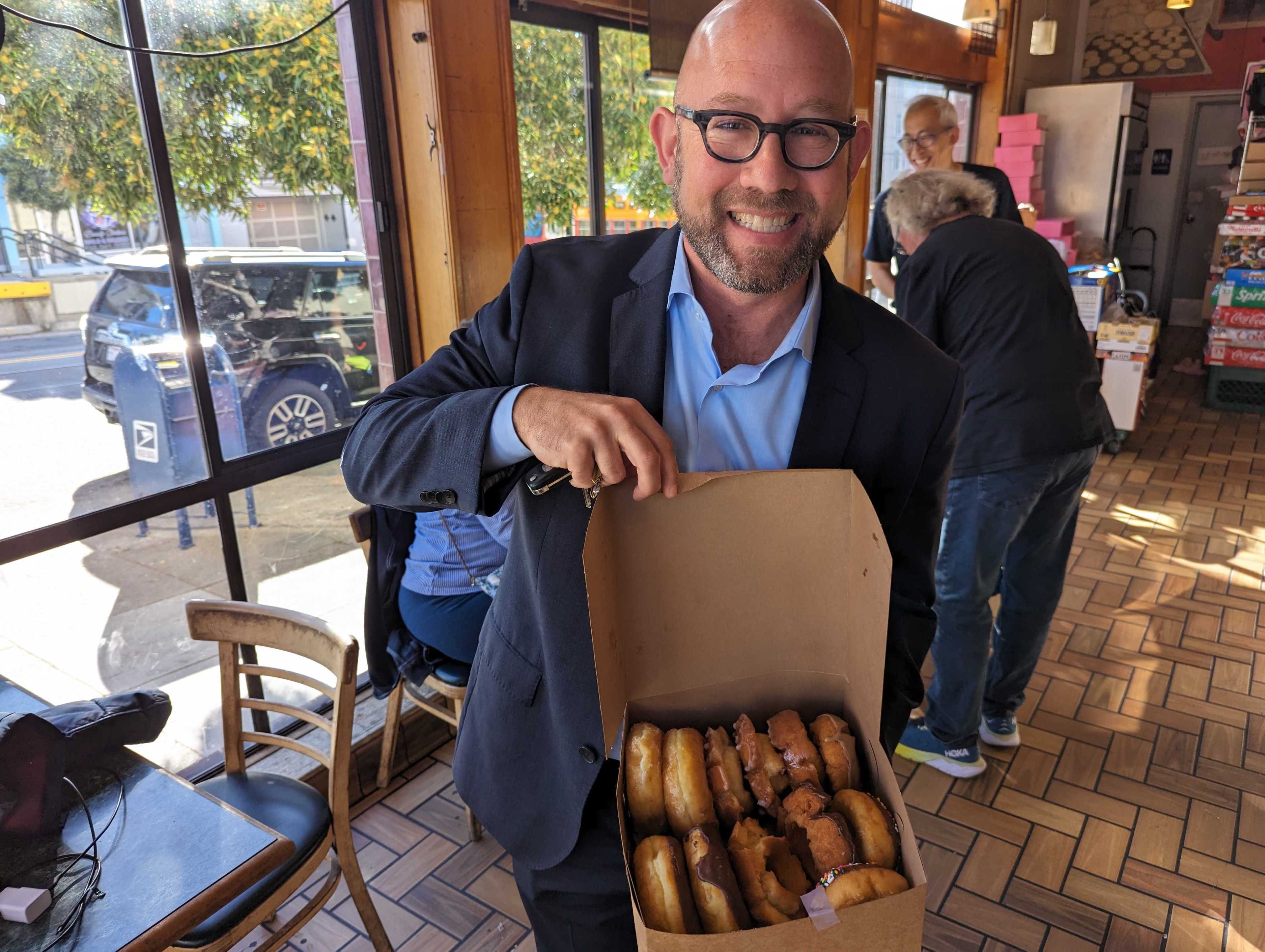 San Francisco Supervisor Rafael Mandelman holds a tray of freshly baked doughnuts Wednesday inside the Happy Donuts shop in Noe Valley.