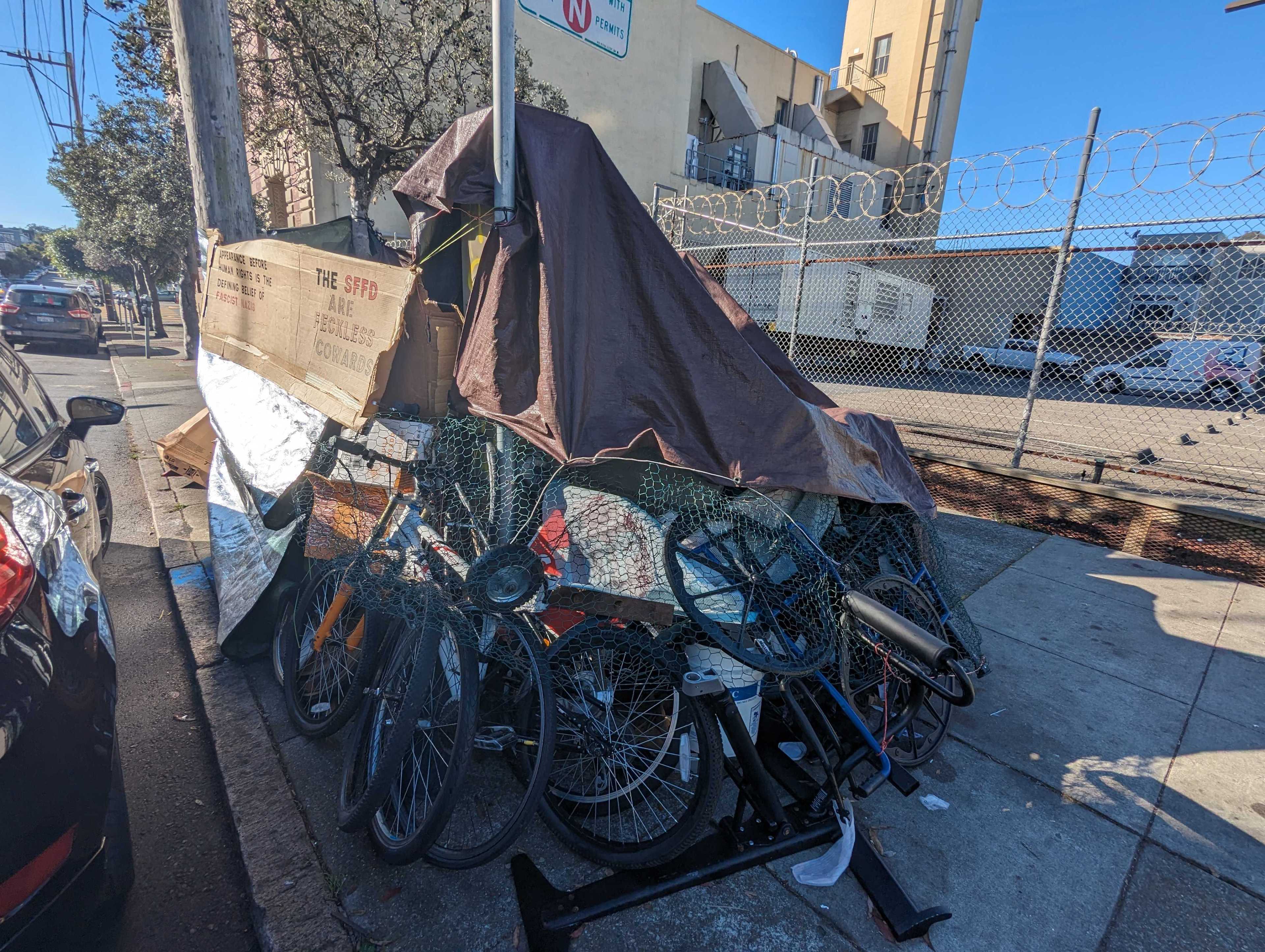 Signs reading &quot;Appearance before human rights is the defining belief of fascist Nazis&quot; and &quot;the SFPD are feckless cowards&quot; sit atop Joseph Adam Moore's encampment on Ninth Avenue north of Geary Boulevard in San Francisco's Inner Richmond neighborhood.