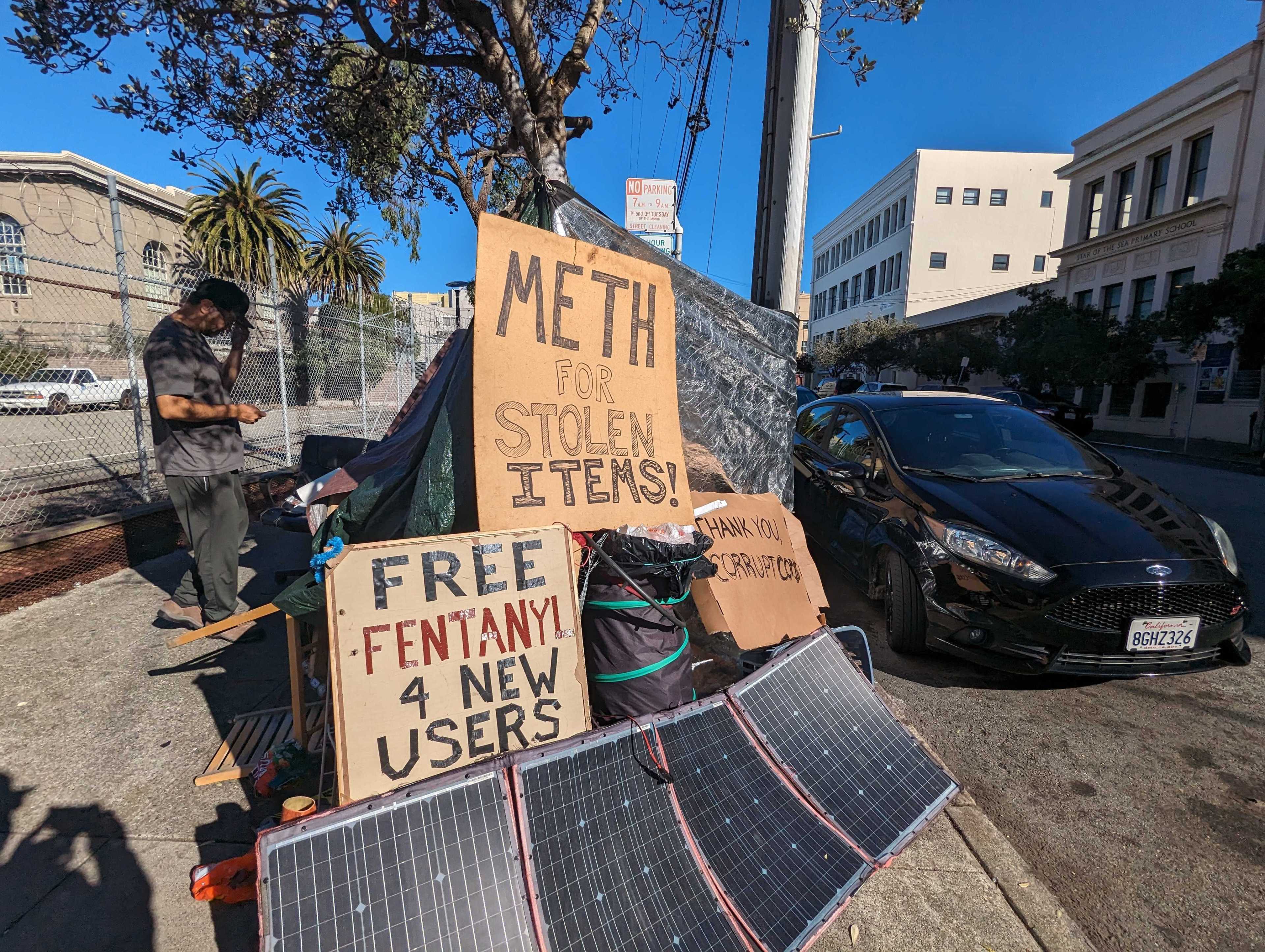 Signs reading &quot;Meth for stolen items&quot; and &quot;free fentanyl 4 new users&quot; sit atop Joseph Adam Moore's encampment on Ninth Avenue north of Geary Boulevard in San Francisco's Inner Richmond neighborhood.