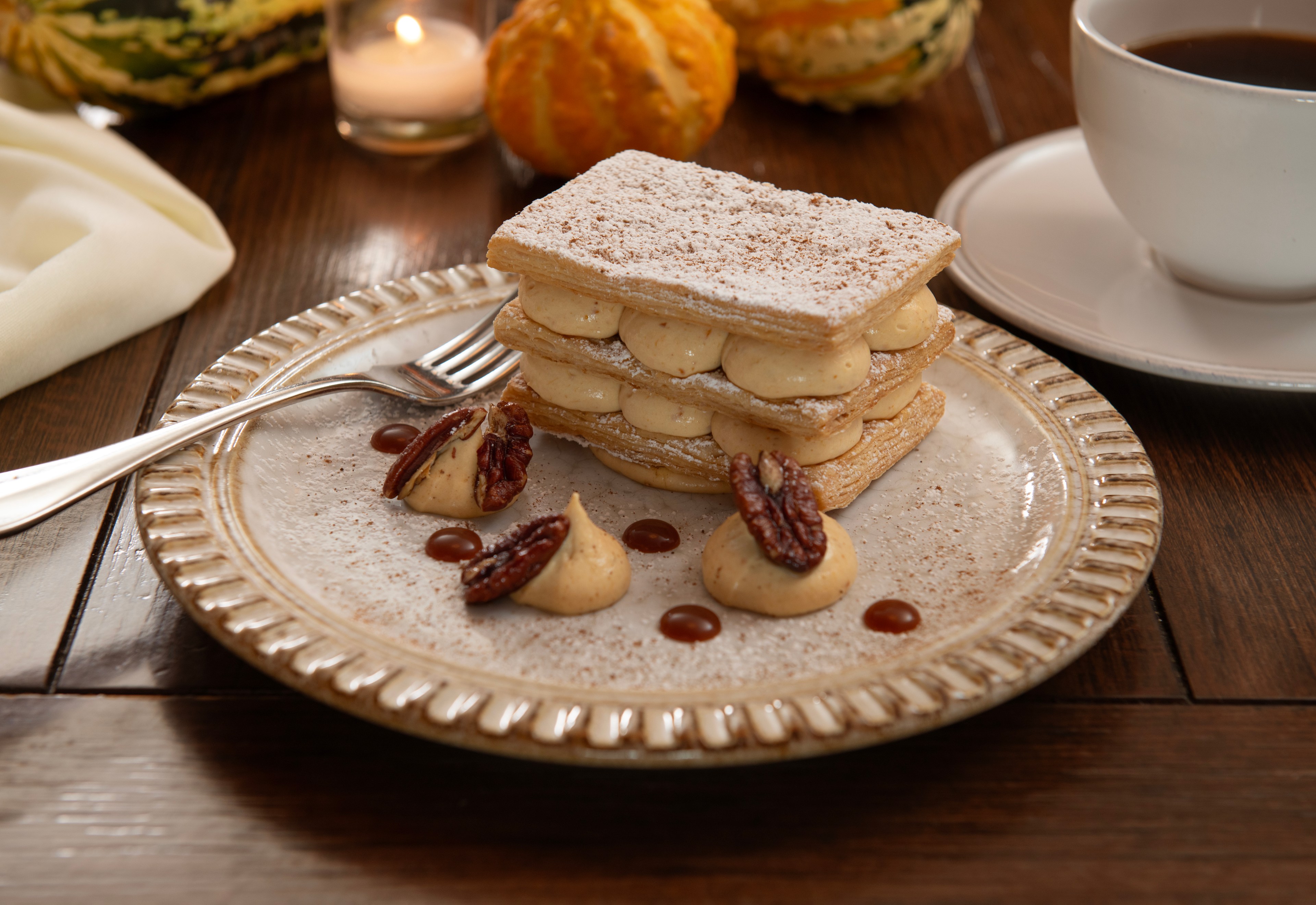 An image of mille-feuille pastry with pumpkin cream sandwiched between layers of pastry, with pecan nut crumbles as garnish. 