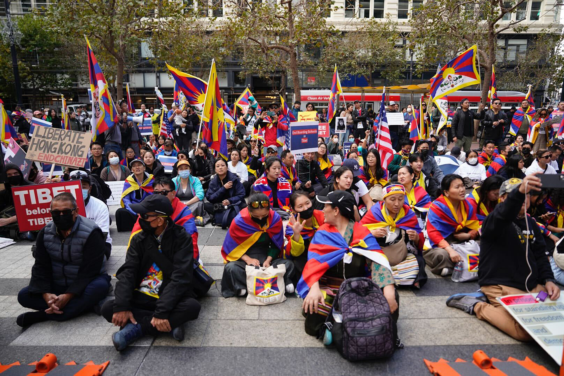 People sit on the ground and wave Tibetan flags during a large protest involving pro-Tibet demonstrators.