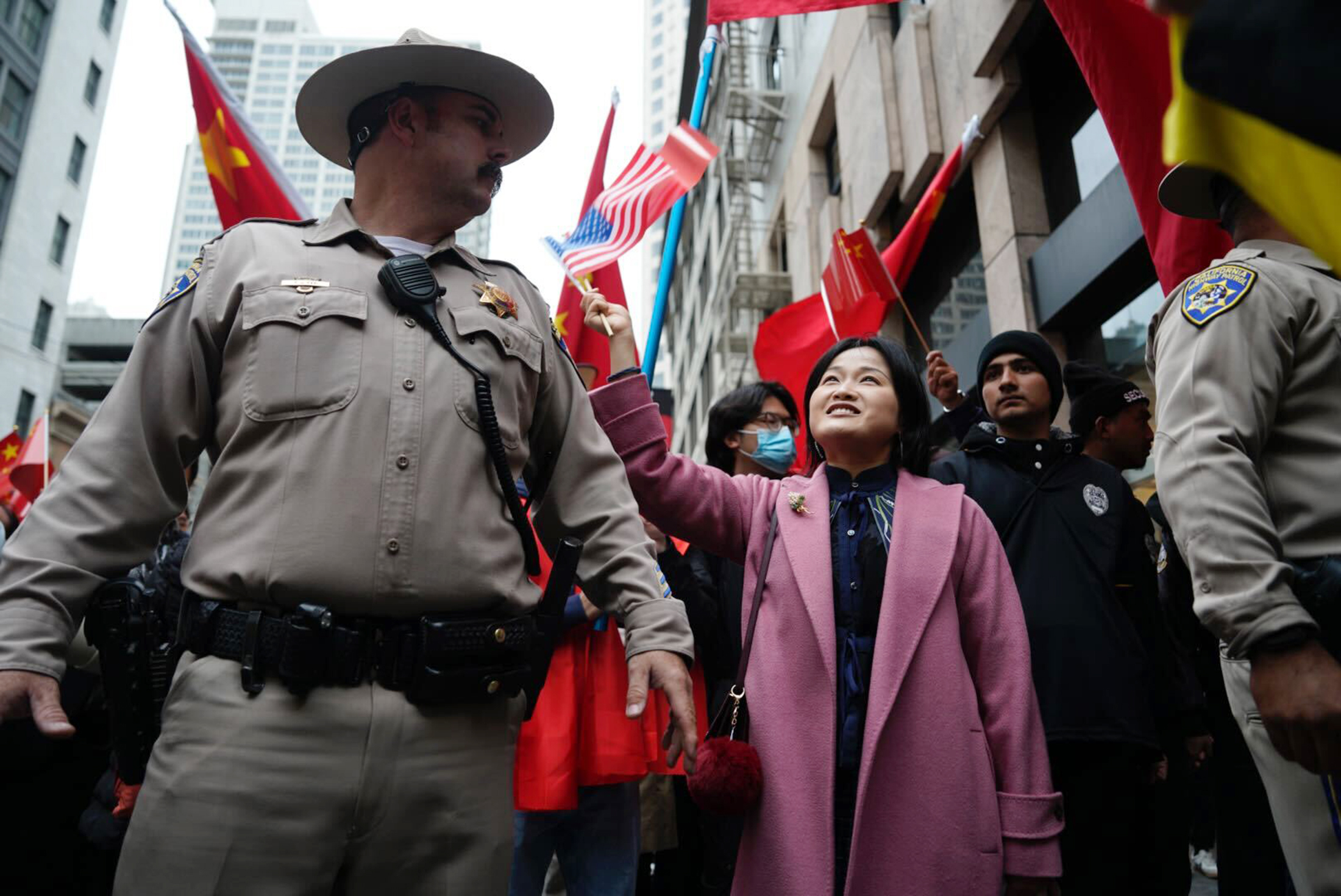 A pro-China protester holds a Chinese flag as California Highway Patrol stands close during a demonstration.