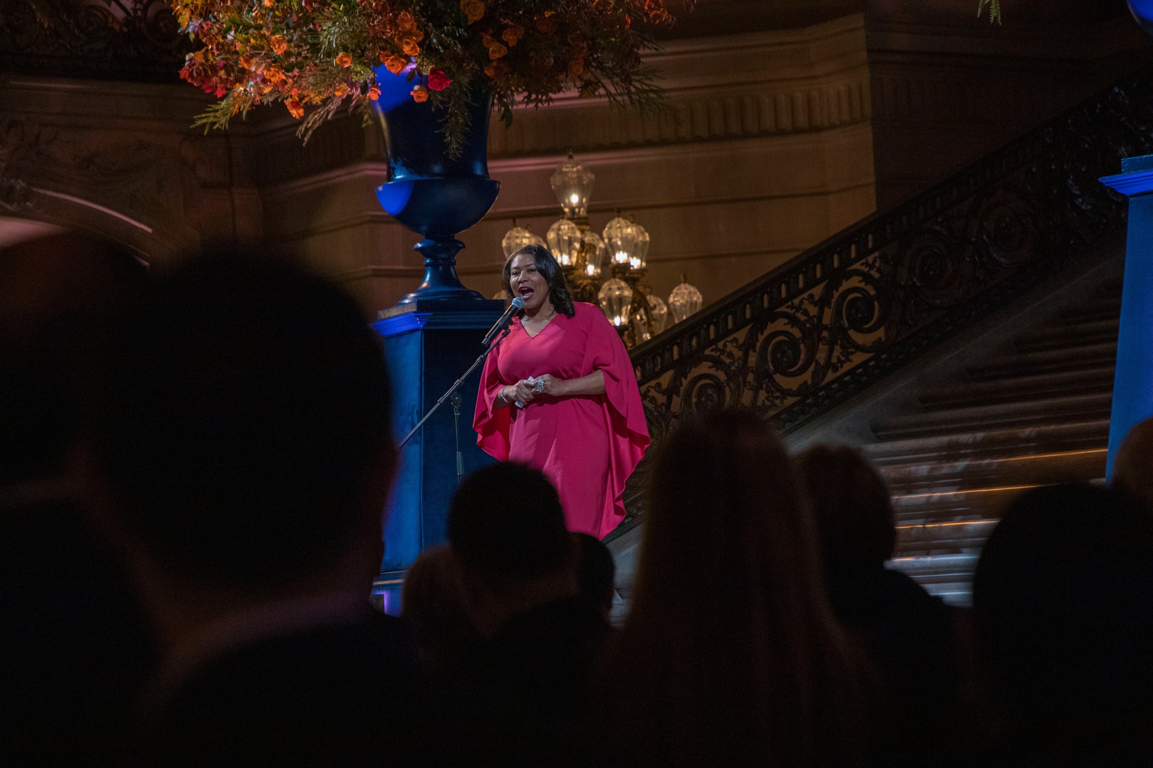 Mayor London Breed welcomes guest inside San Francisco City Hall in a red dress.