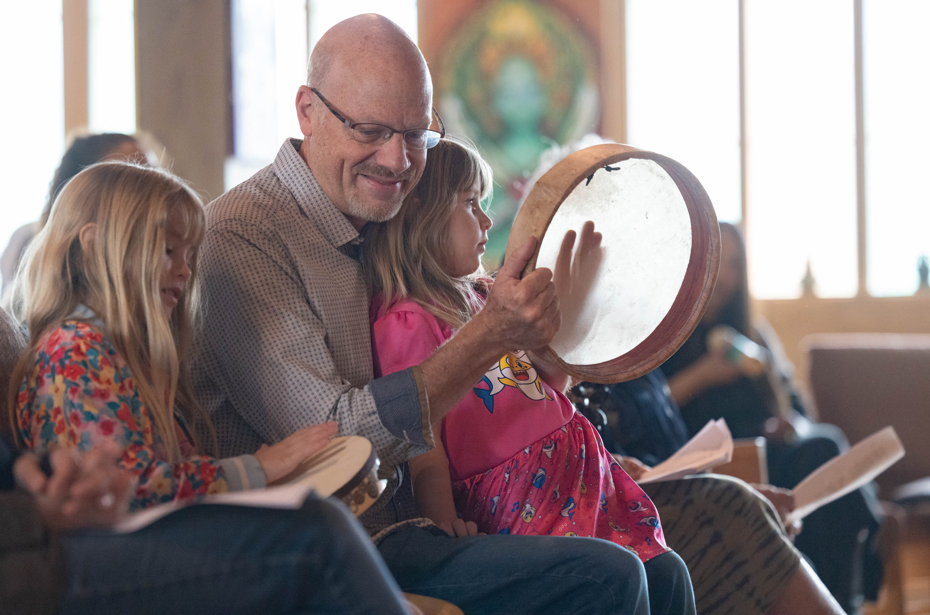 A man and 2 children play a drum during a church service