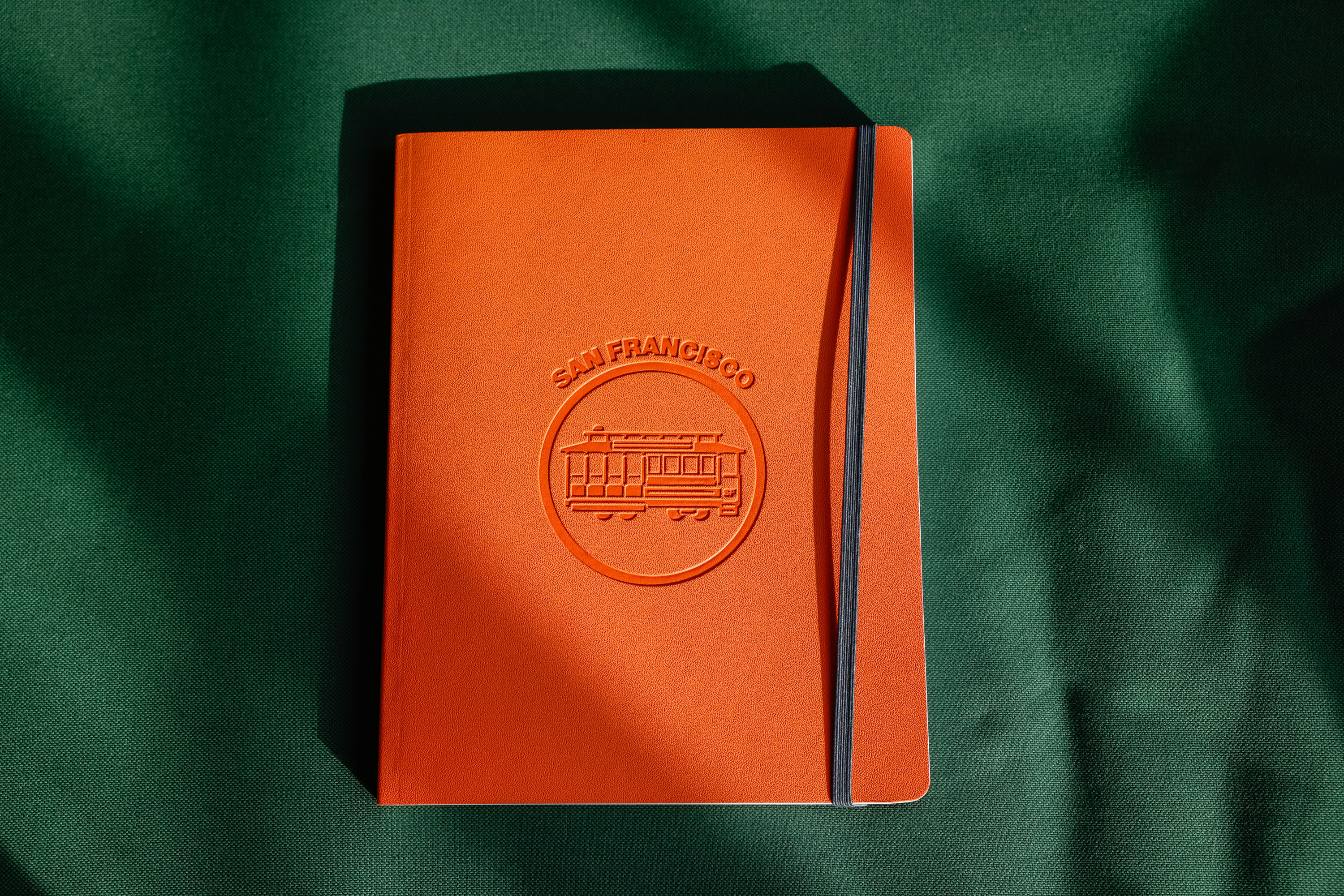 An orange leather notebook featuring an outline of San Francisco’s cable car and the words “San Francisco” above it.