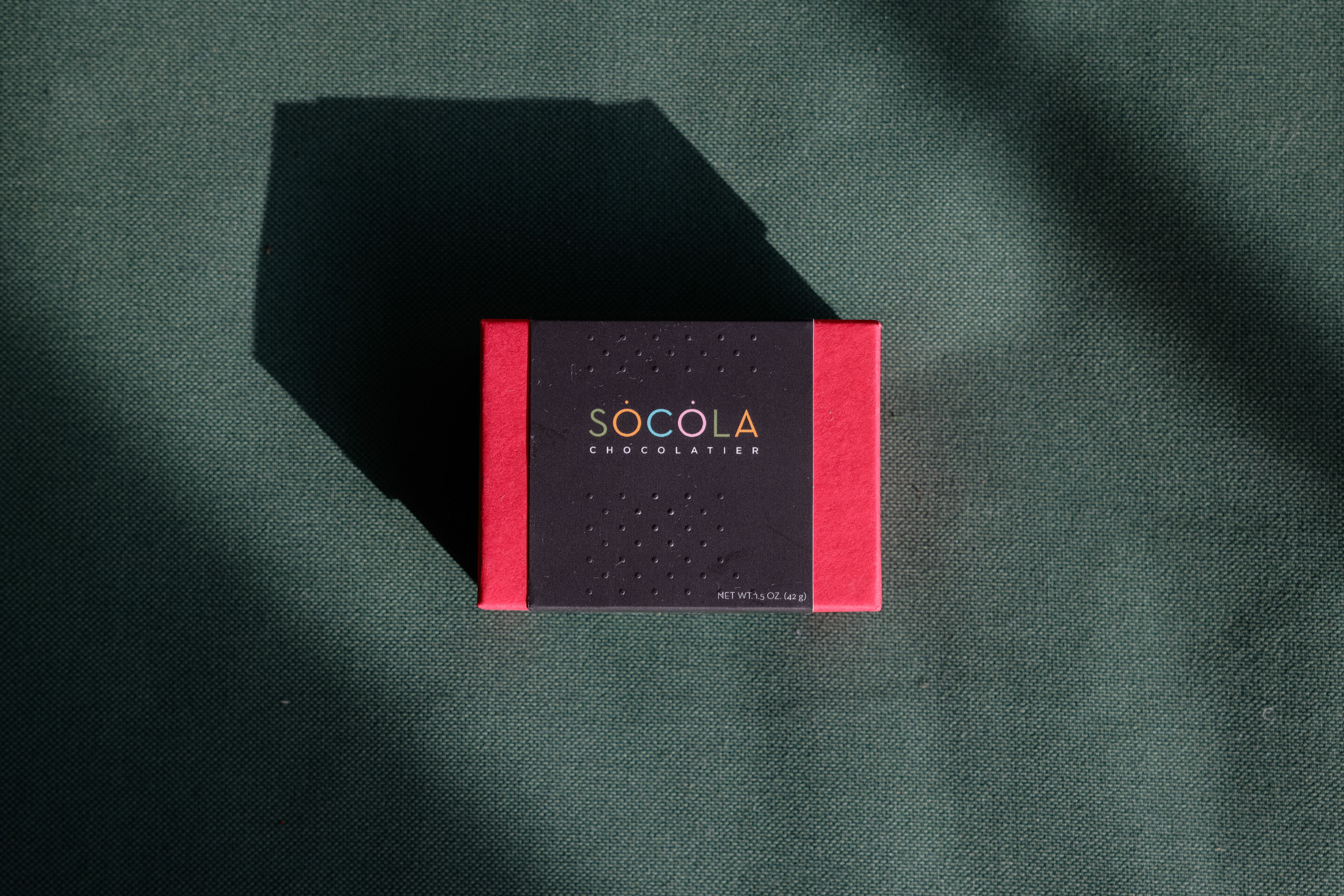 A top-down product shot Socola Chocolatier in a red box.