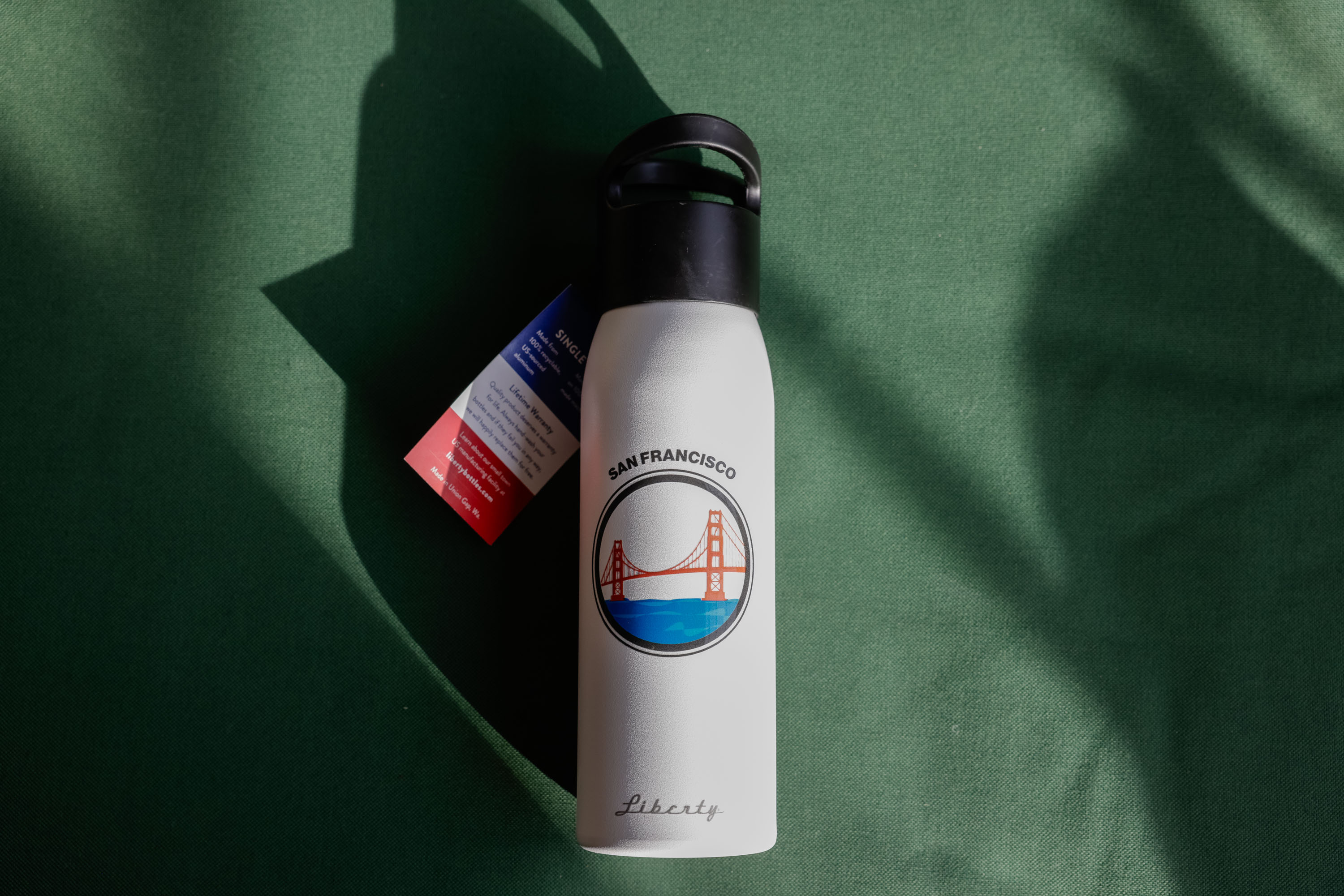 A top-down product shot of a white San Francisco-themed water bottle with the Golden Gate Bridge design.