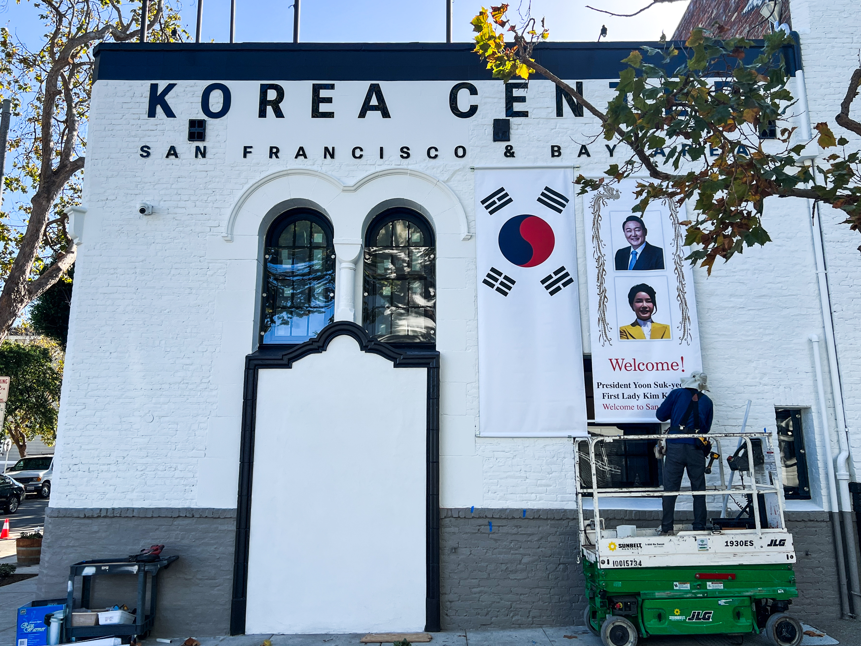 A worker on a scaffold hangs a banner welcoming President/First Lady of Korea, Kim Keon-hee on the building of the Korea Center in San Francisco.