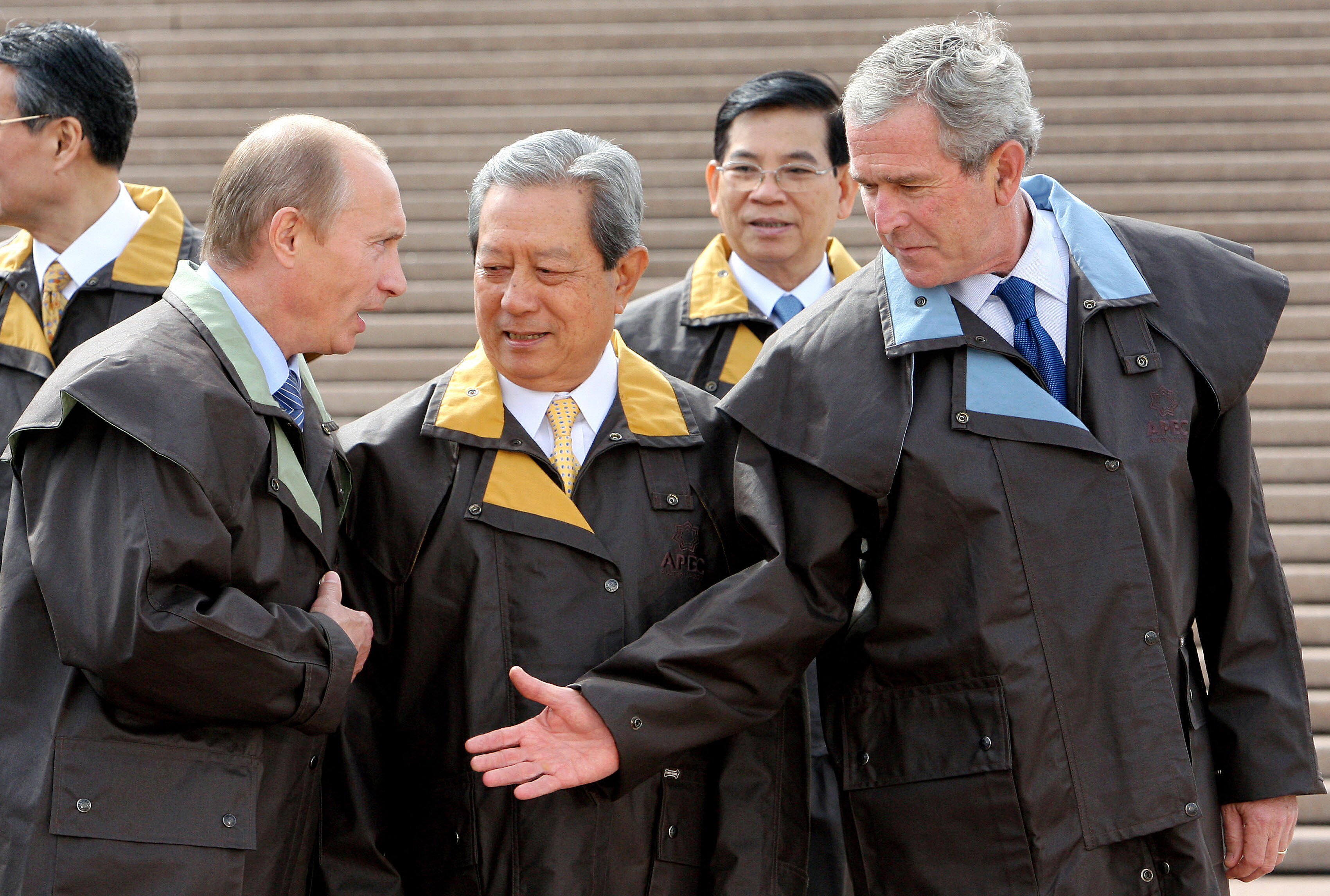 US President George W. Bush greets Russia's President Vladimir Putin while wearing matching raincoats as they wait to take a group picture in Australia.