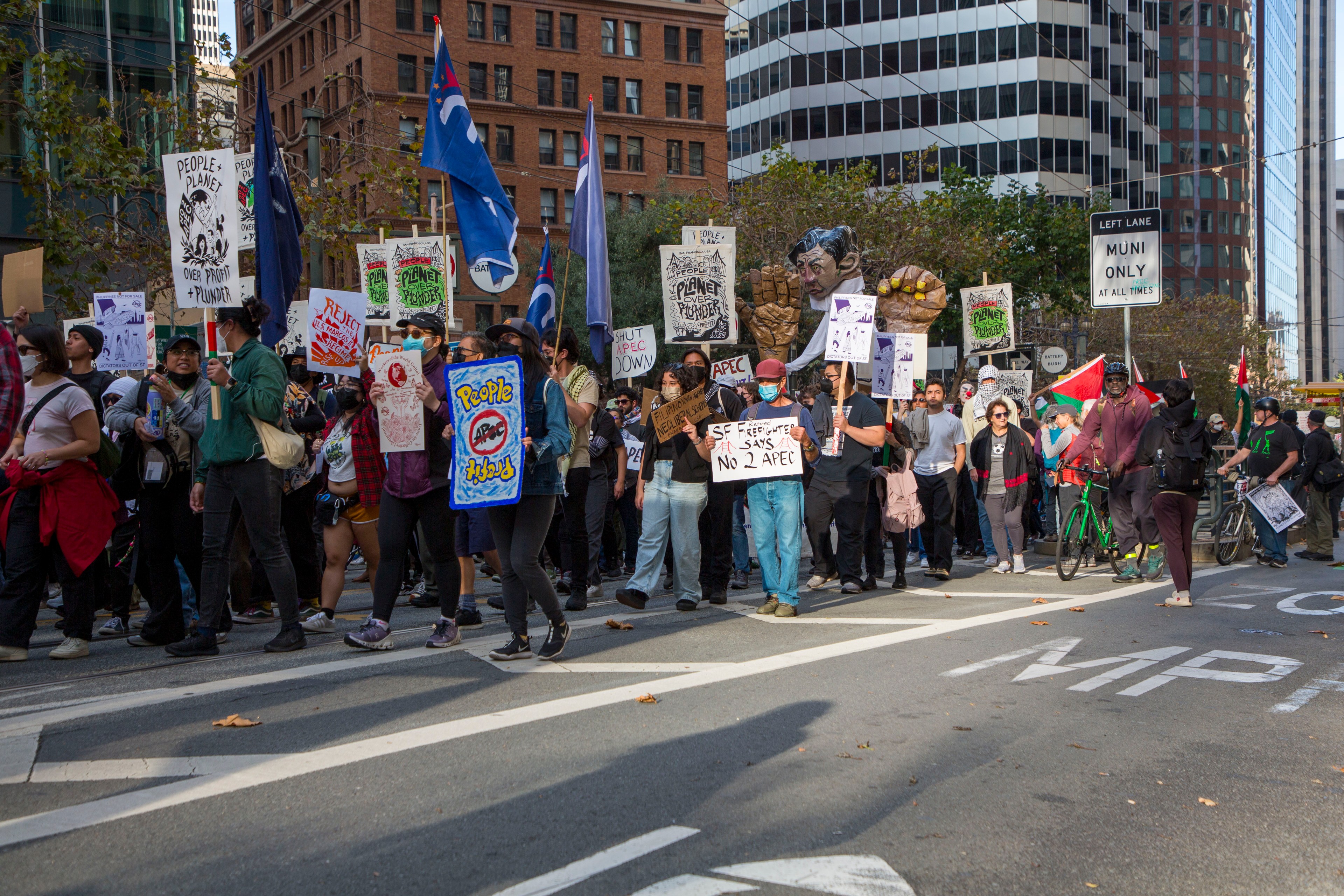 Thousands of people are protesting APEC on Market Street in San Francisco, holding signs against the conference.
