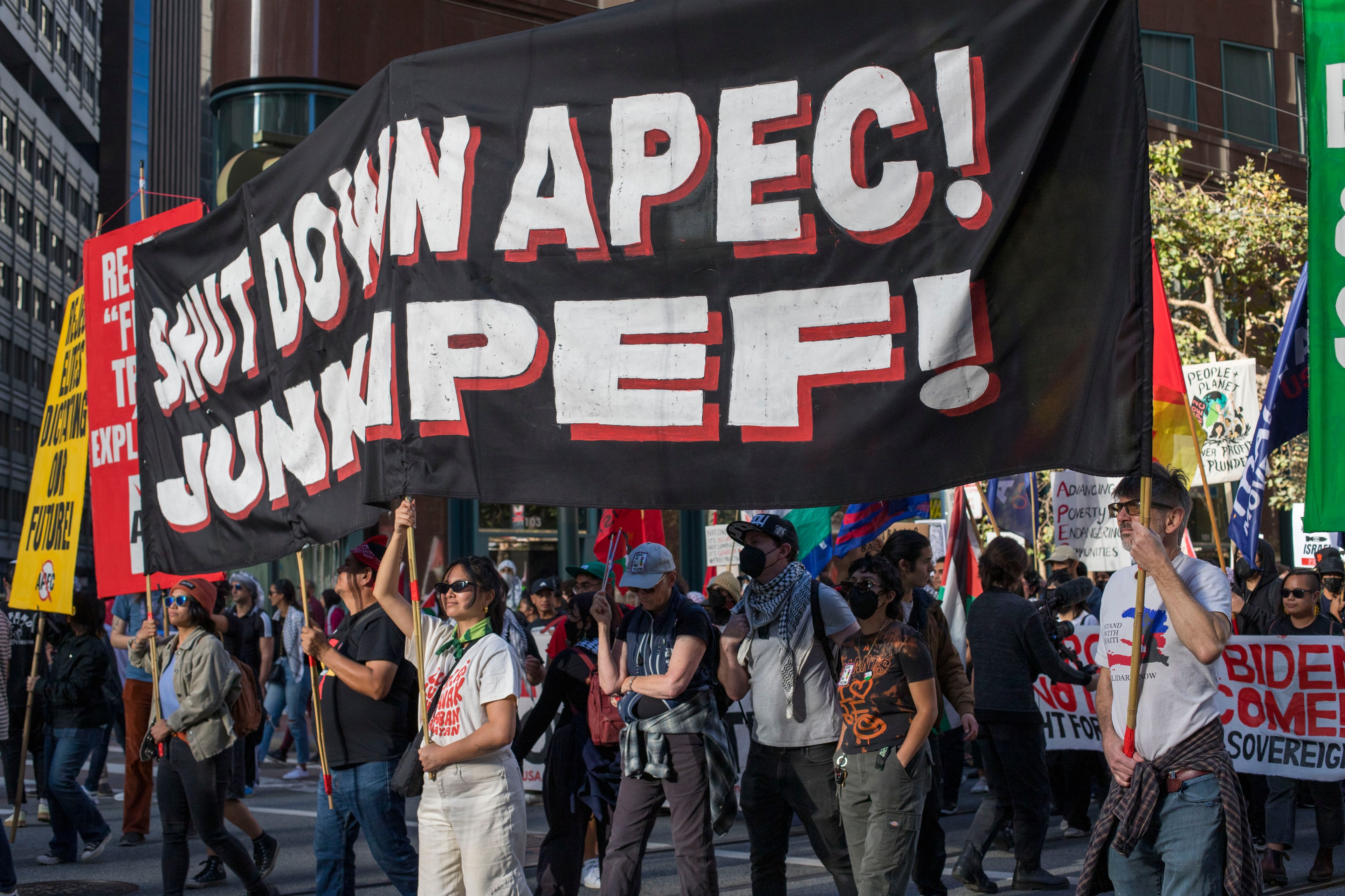 A banner carried by individuals that say &quot;Shut down APEC! Junk IPEF&quot;.