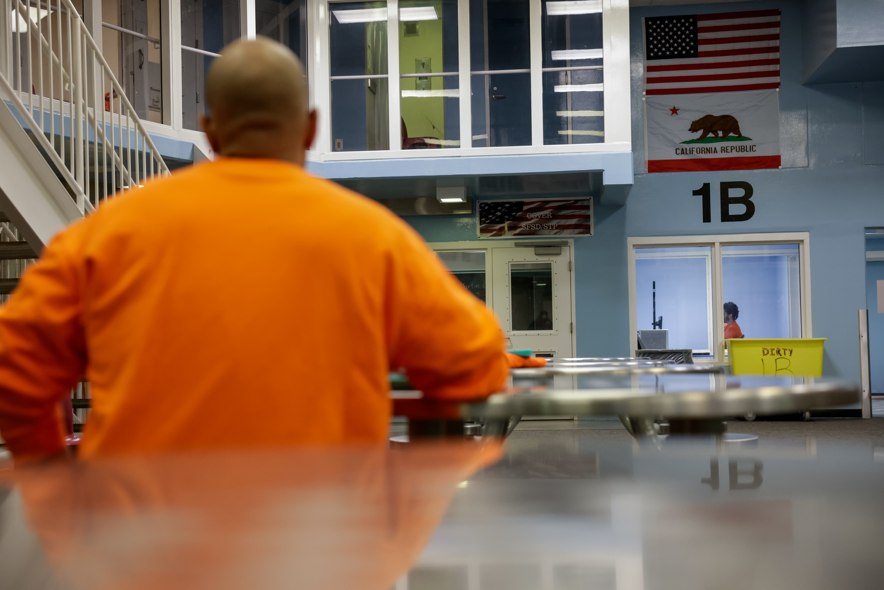 An inmate sits at a table in the communal room of the jail cell block.