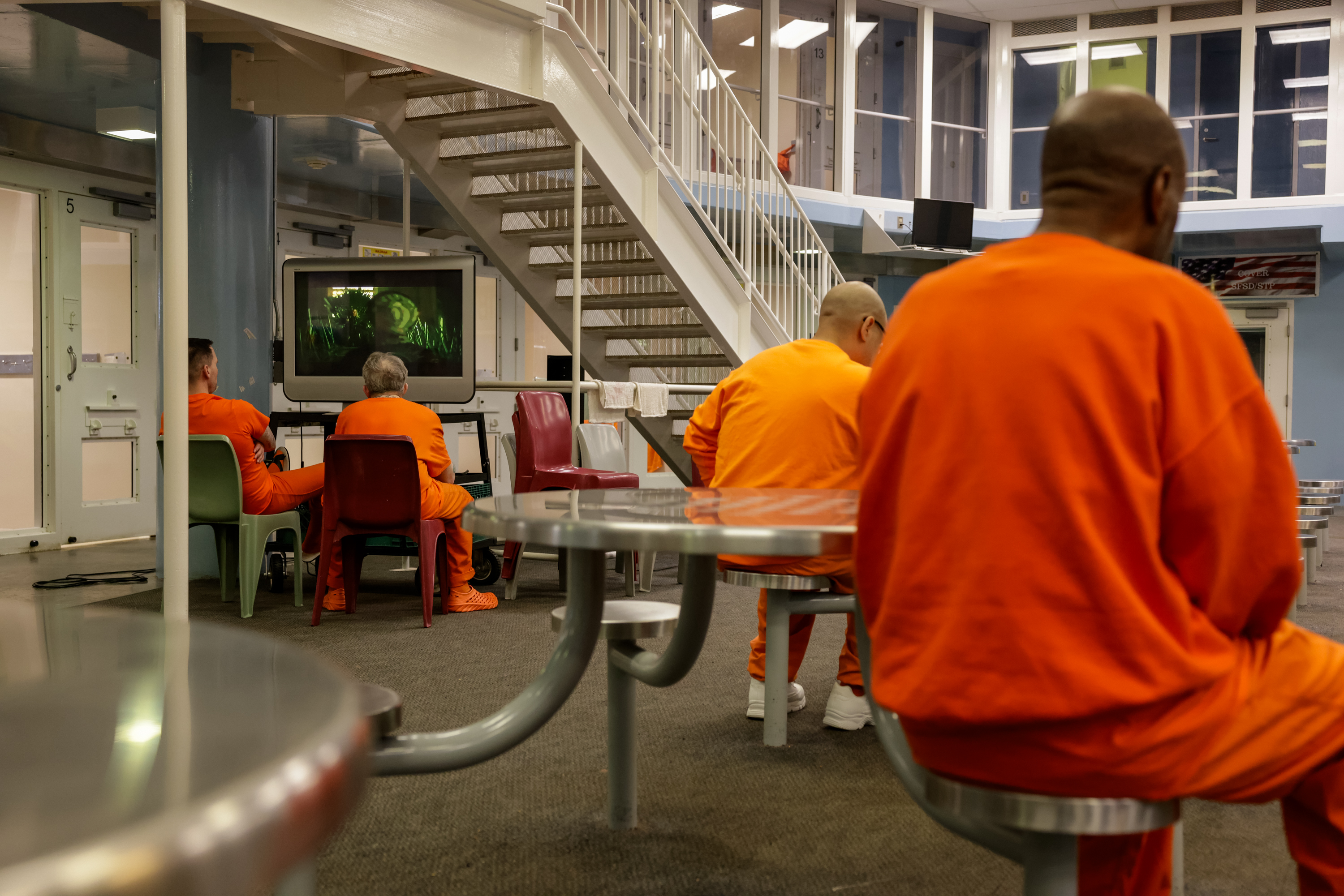 Inmates sit at a table in the communal room of the jail cell block.