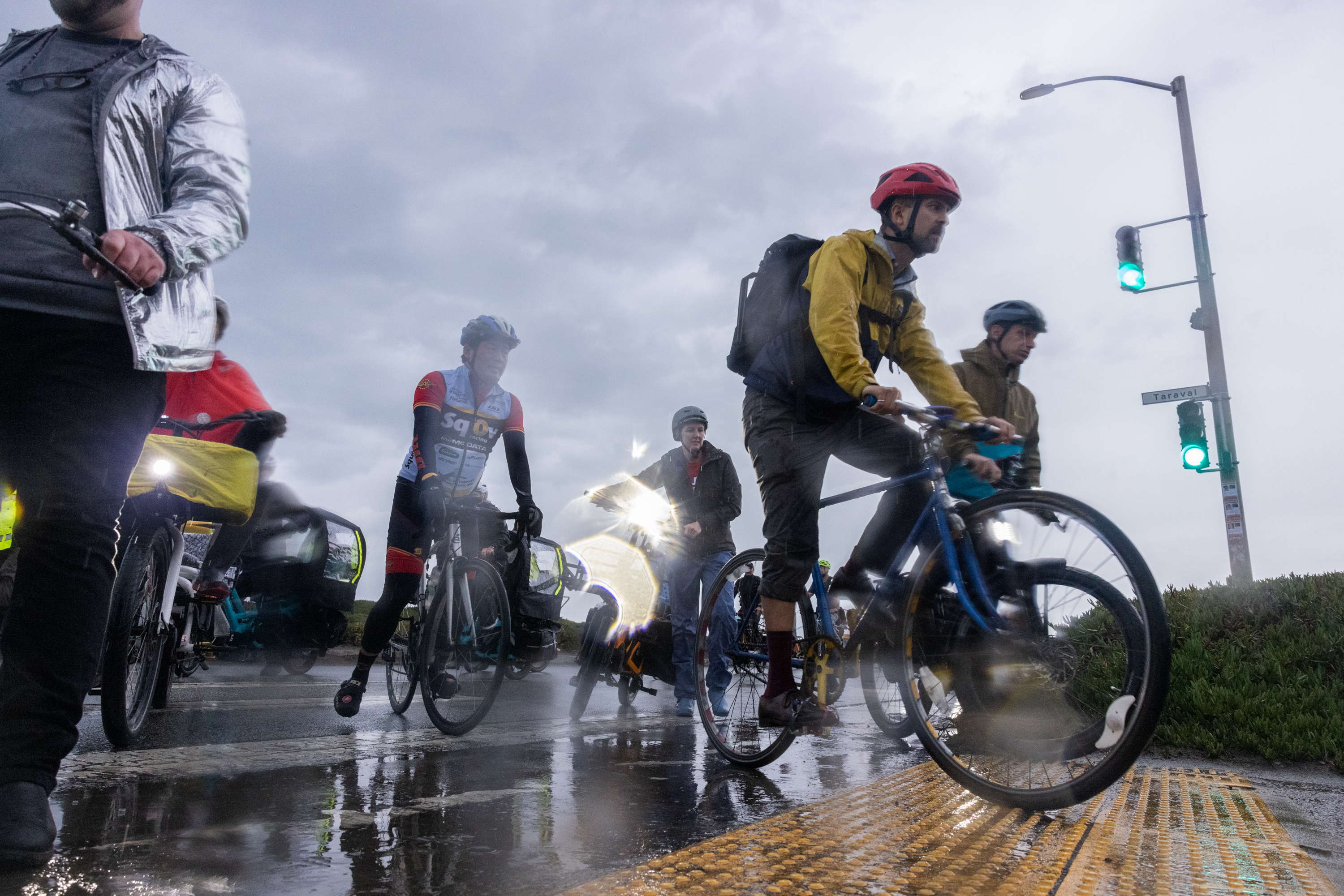 People bike through the Great Highway in the rain.