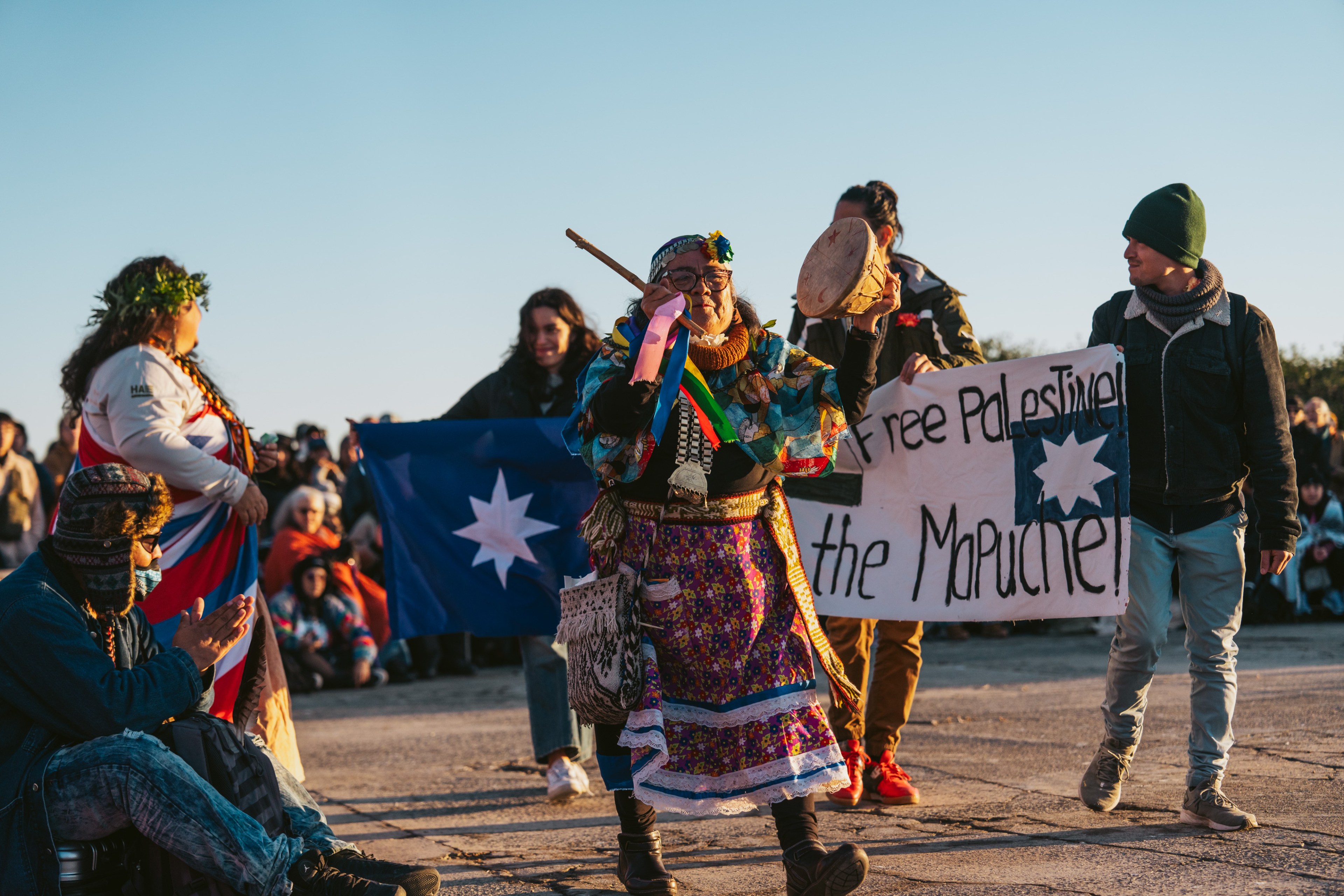 Dancers wearing indigenous regalia hold up a sign that reads, &quot;Free Palestine.&quot;