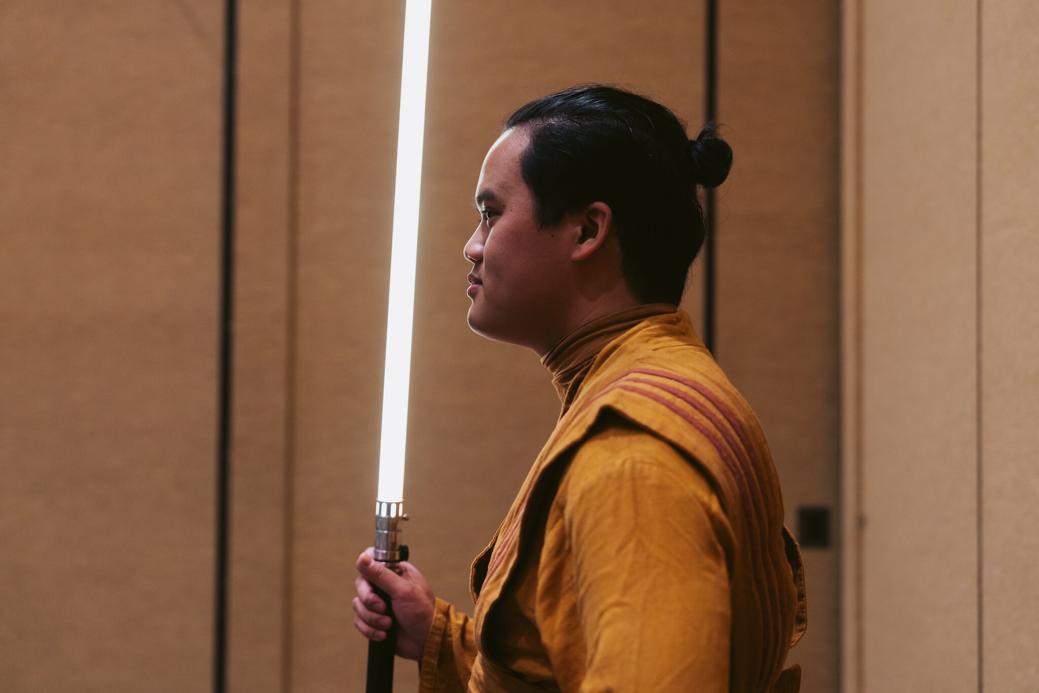 a man in a robe stands in profile holding a light saber