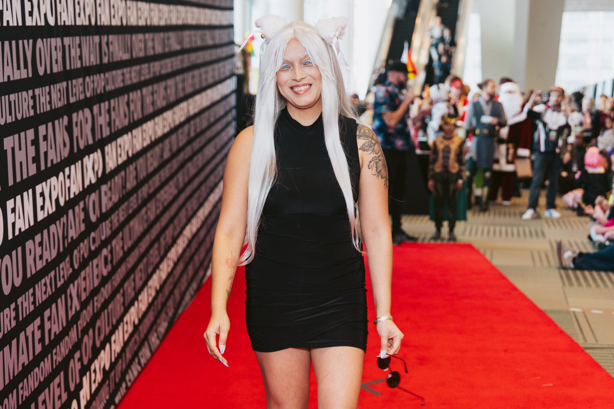 A smiling woman in costume walks down a red carpet.