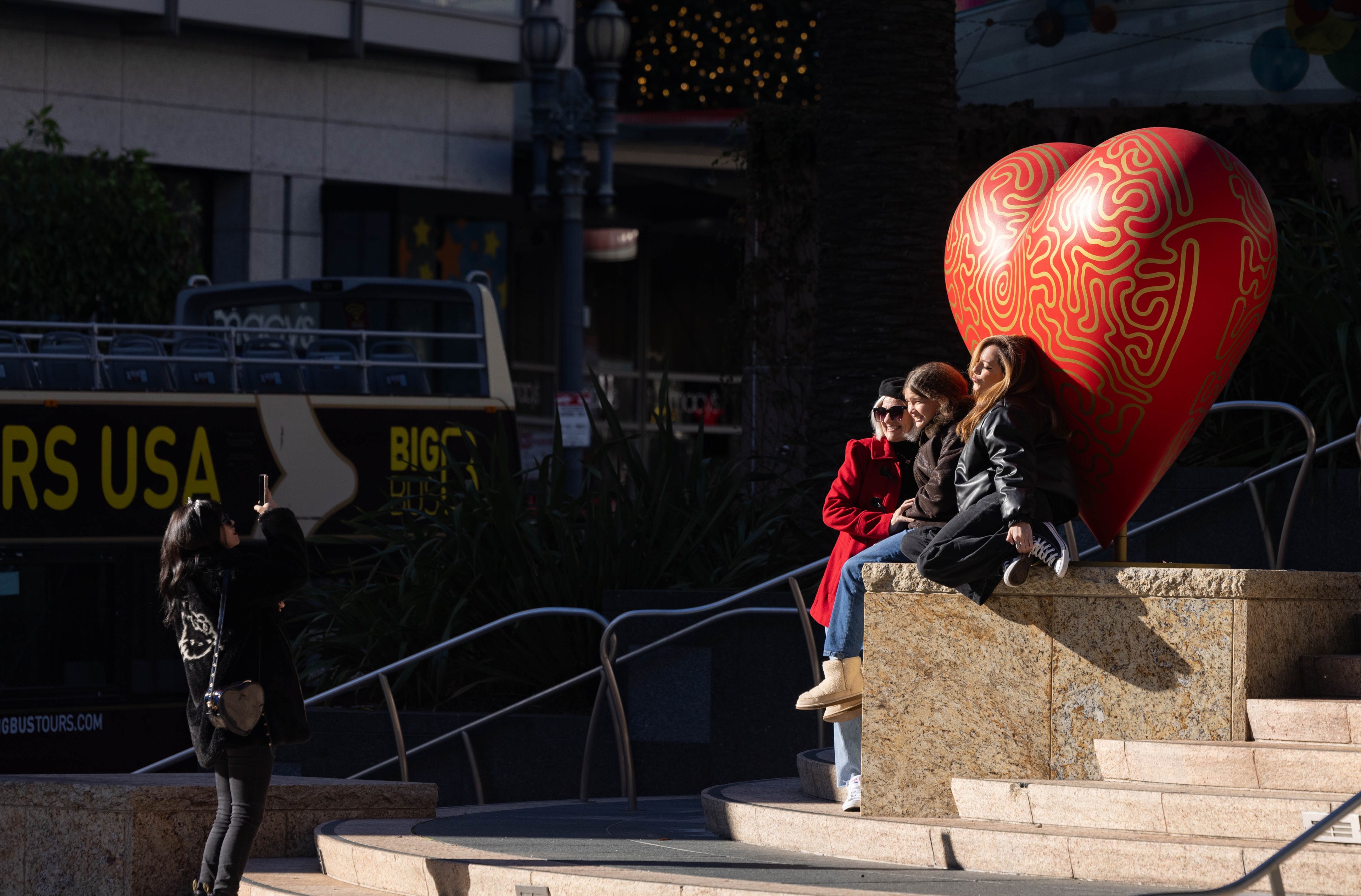 Woman sit in Union Square beside a heart statue.
