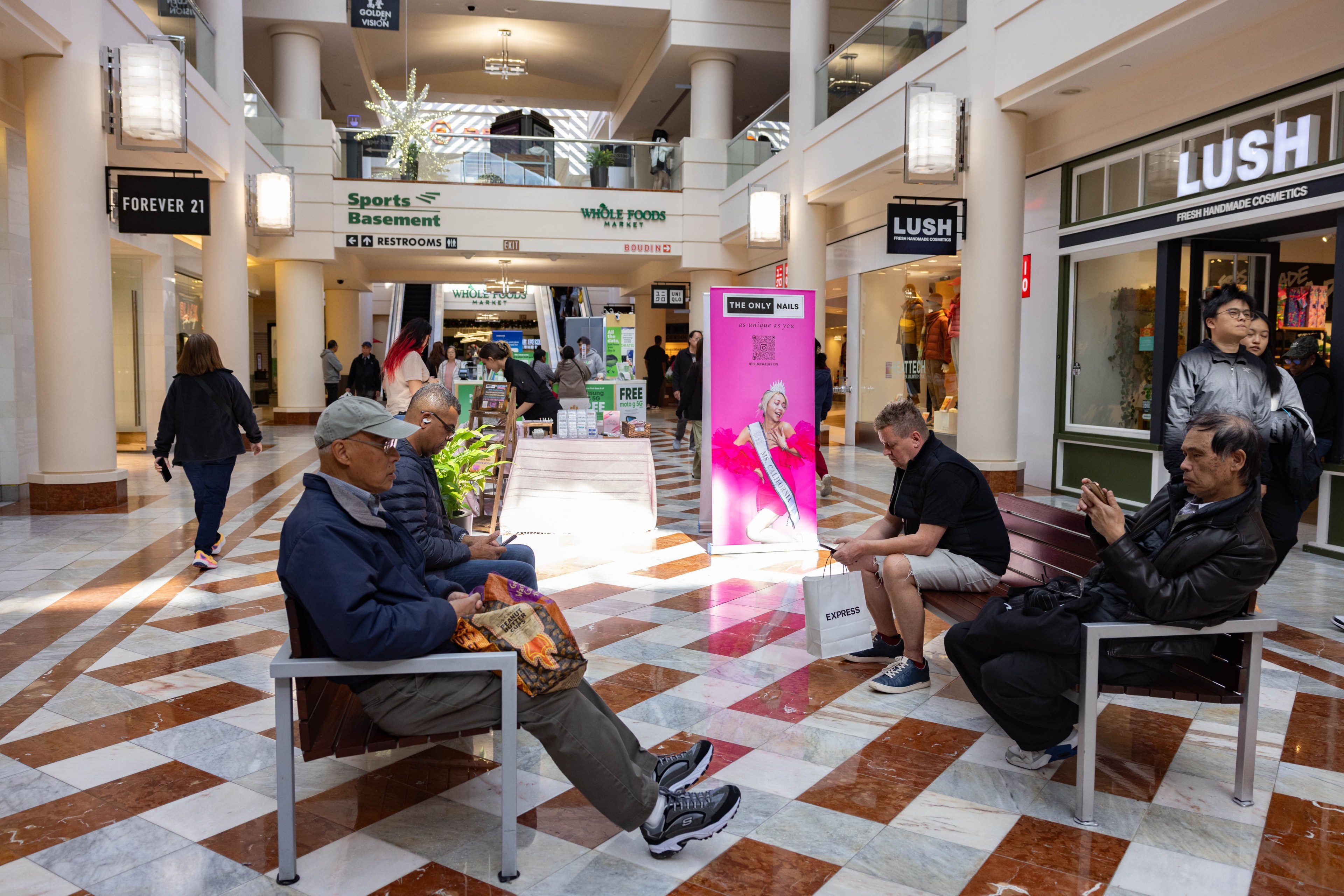People sit at four benches in Stonestown Galleria.