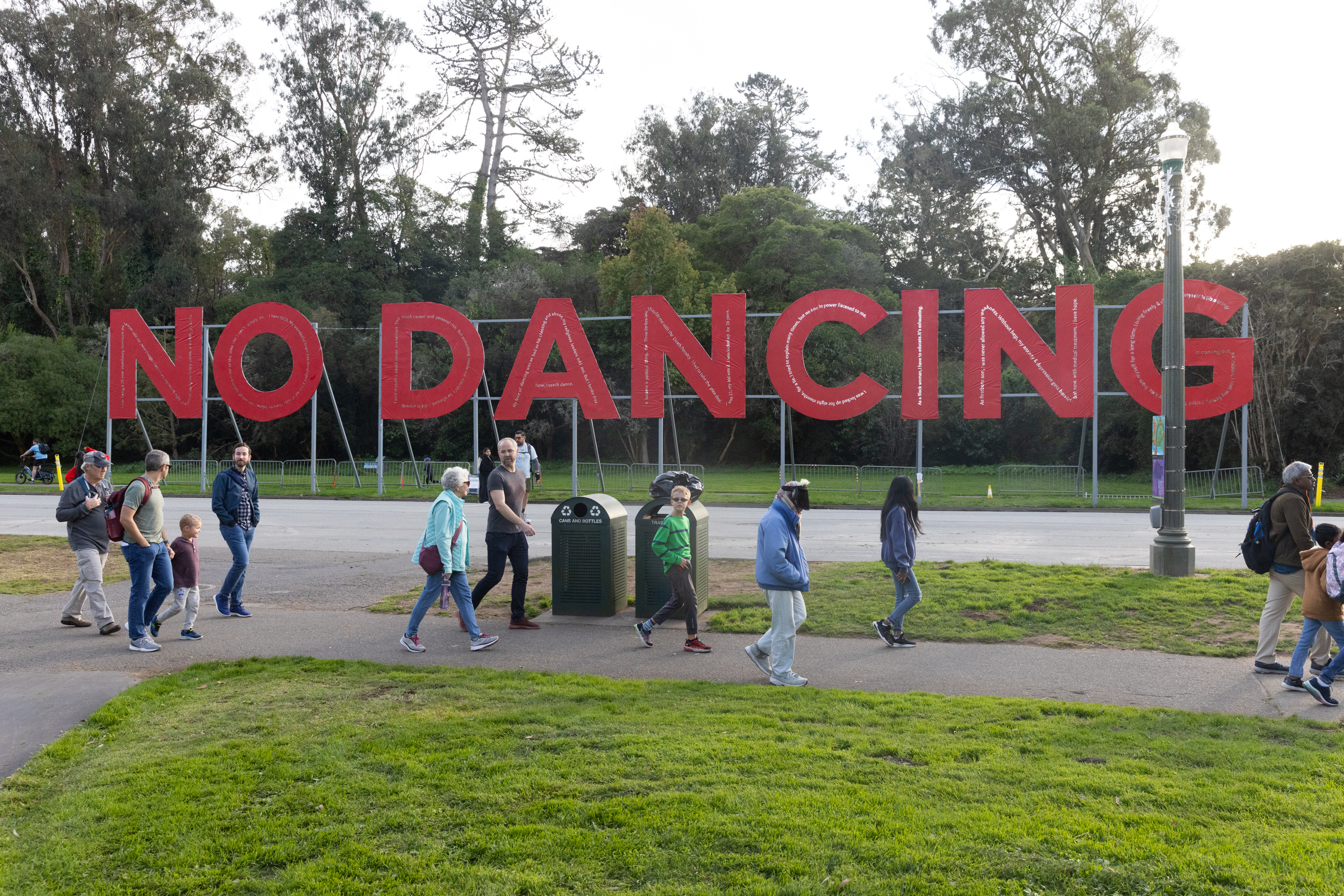People walk pas a huge red sign that says &quot;No Dancing&quot; in Golden Gate Park.