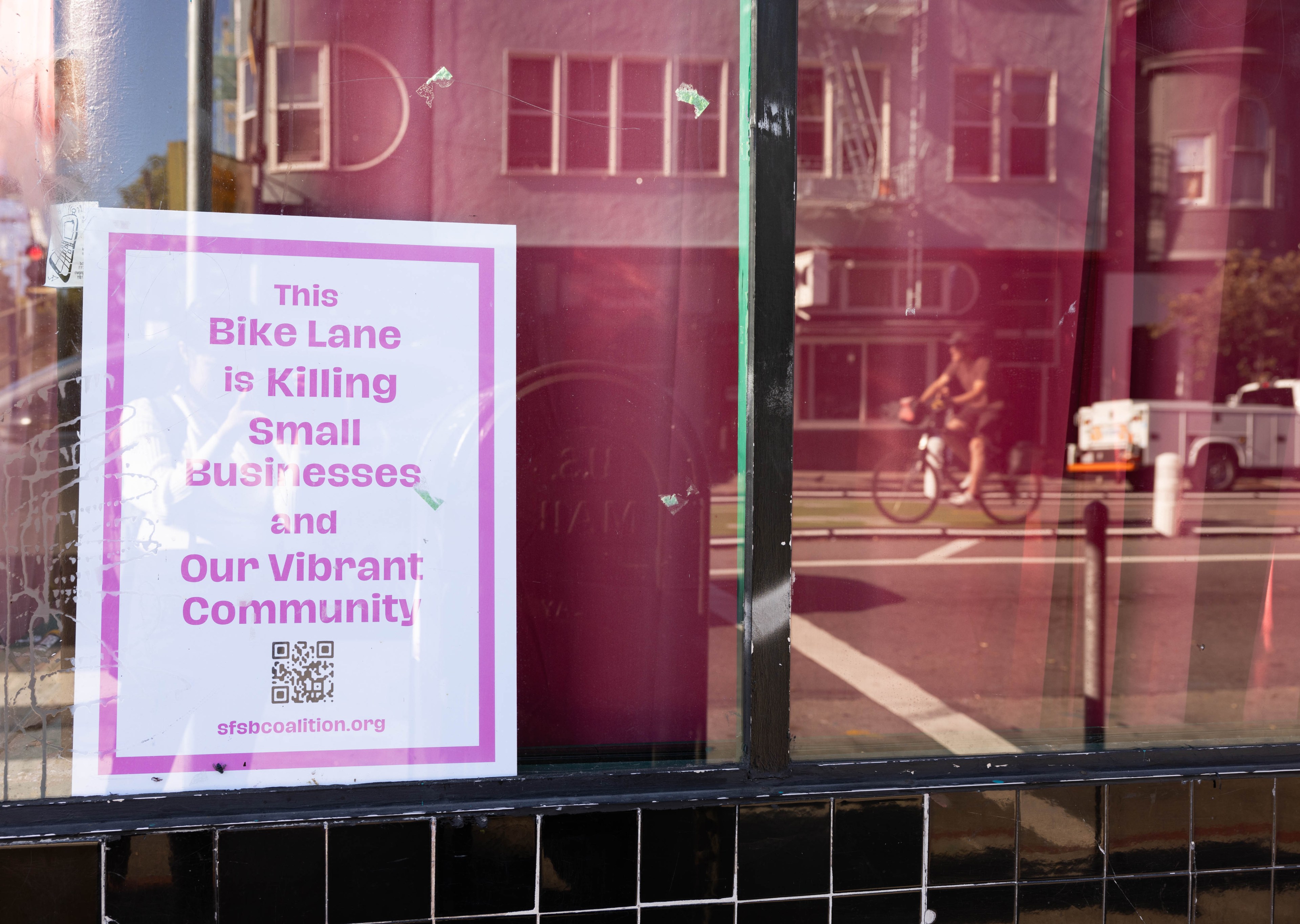 A sign with hangs from a window of a bar that is closing its doors because of a controversial bike lane.
