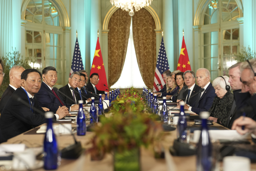Chinese and U.S. leaders meet at a long table in a fancy estate. 