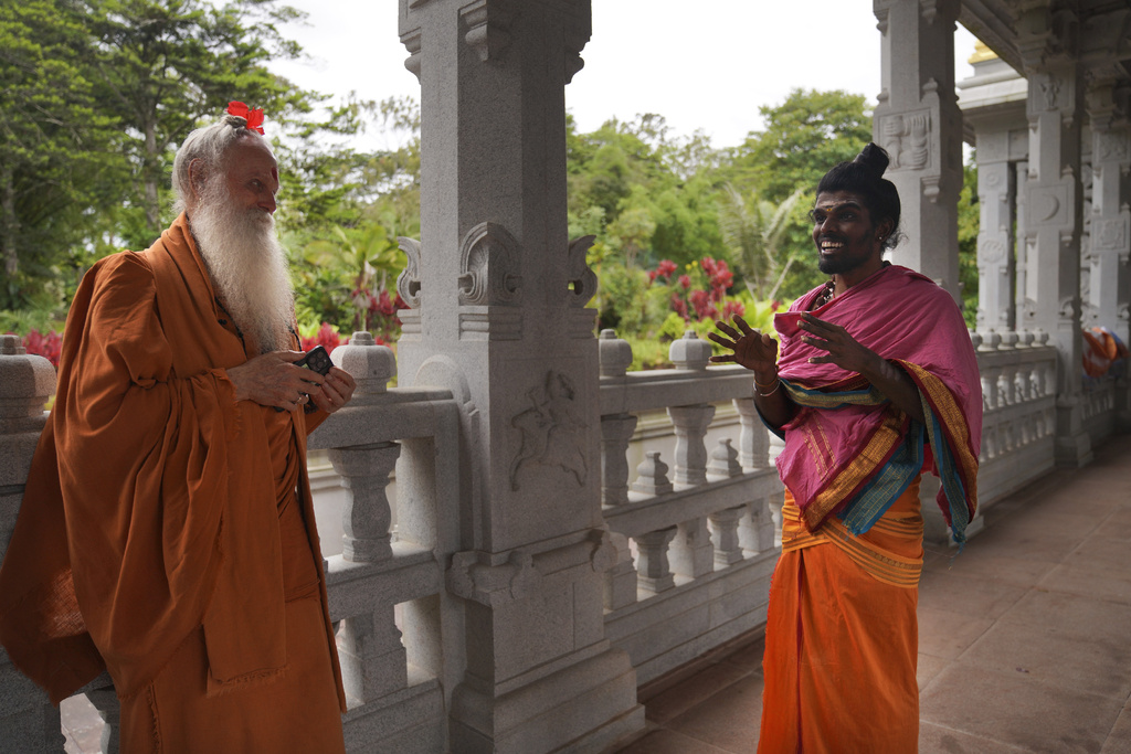 Two men in orange robes on the veranda of a temple.