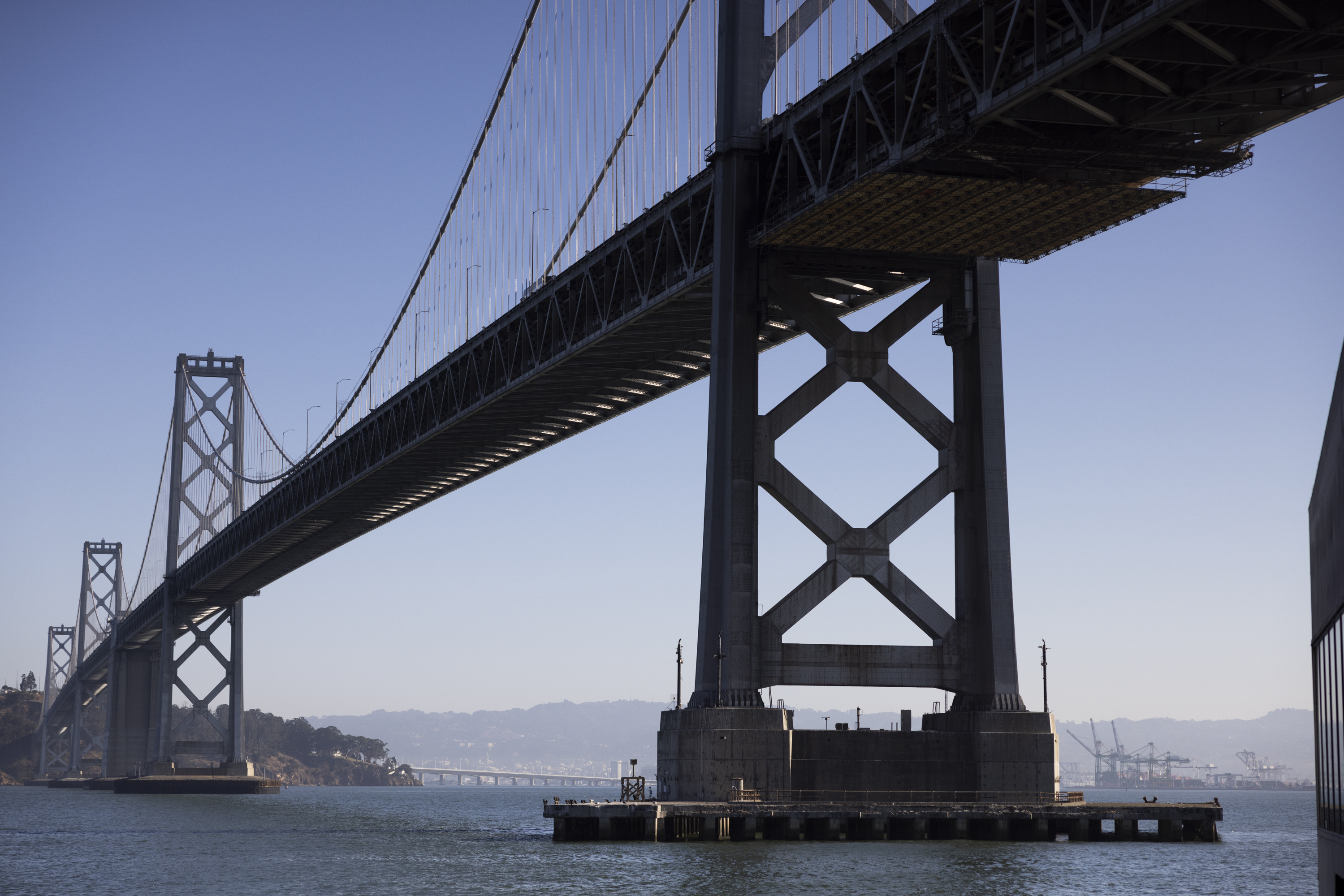 A view from below the The San Francisco-Oakland Bay Bridge and Yerba Buena Island on a sunny afternoon.