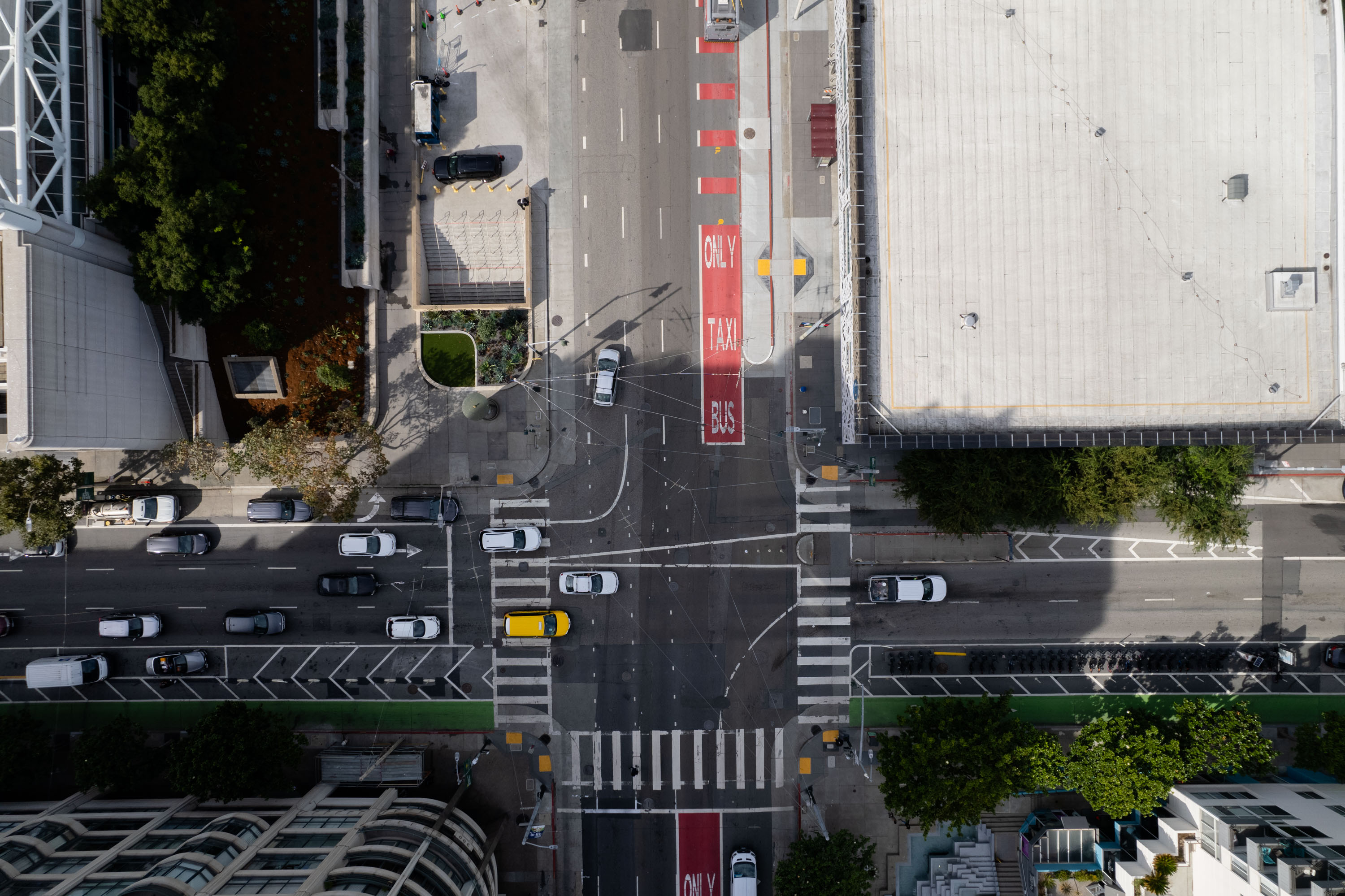 Aerial view of a city intersection with cars at a stoplight and dedicated bus lane marks.