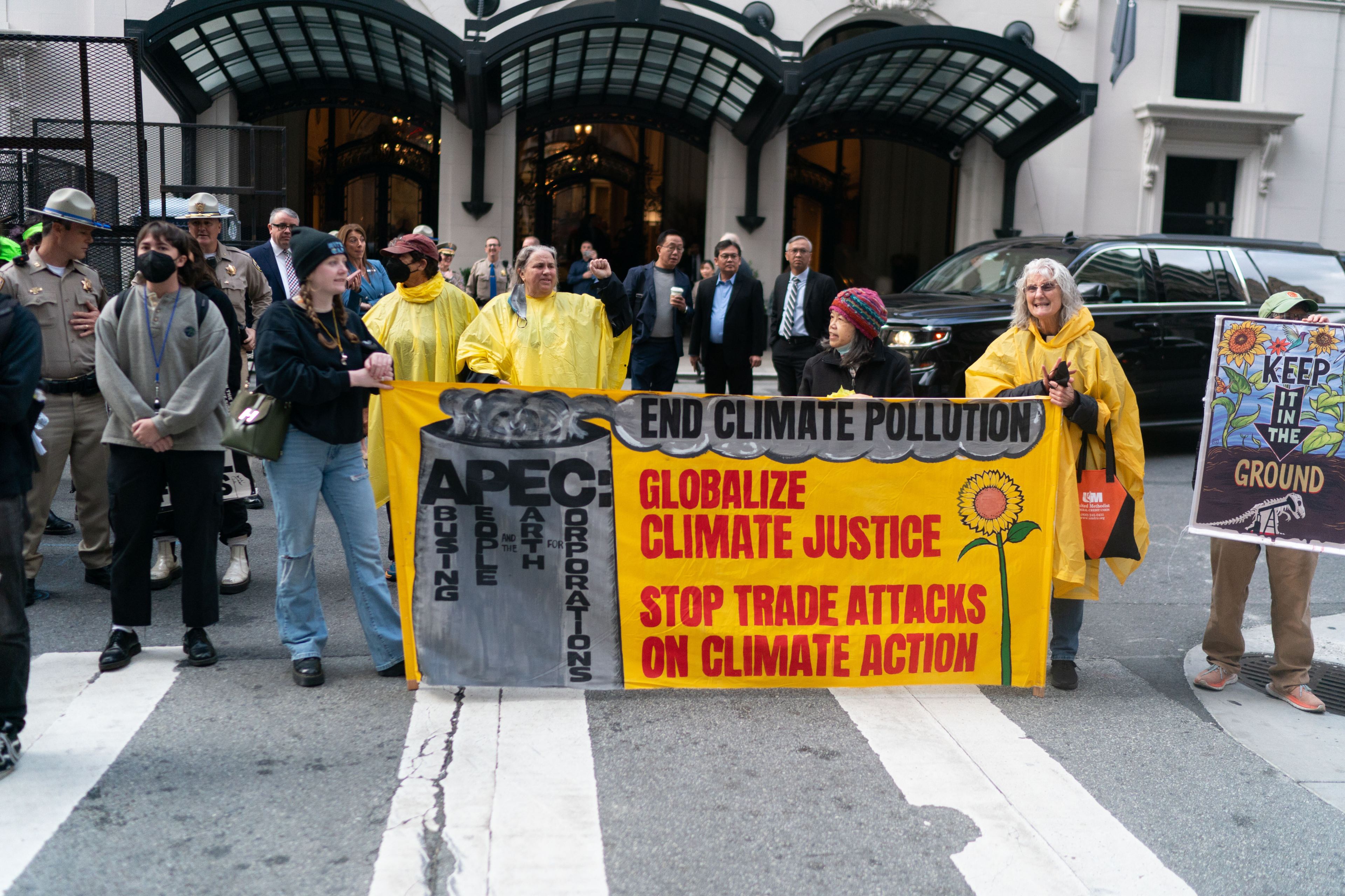 Protesters stand in the middle of the street with and &quot;End Climate Pollution&quot; banner.