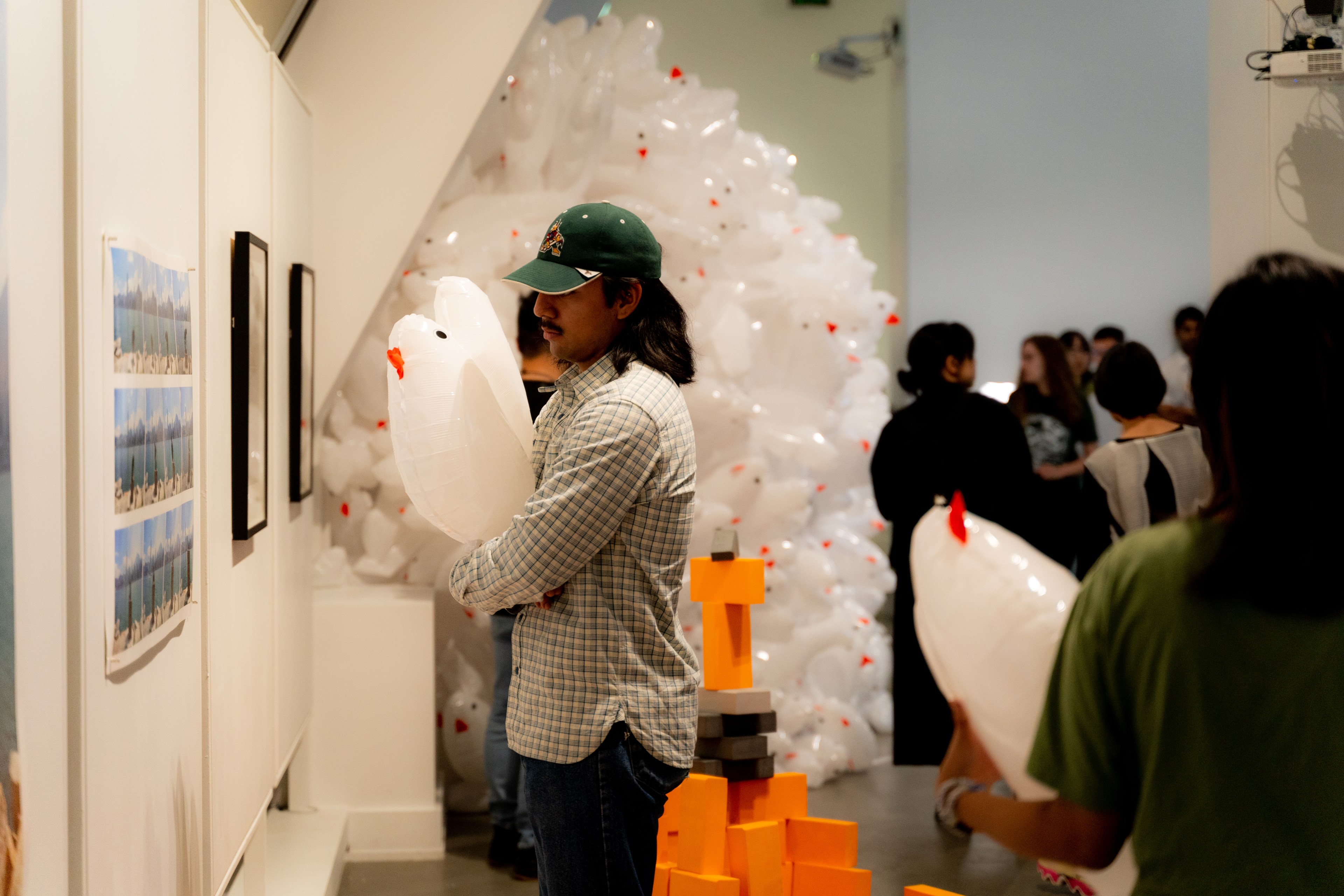 A man holds an inflatable pigeon in an art gallery.