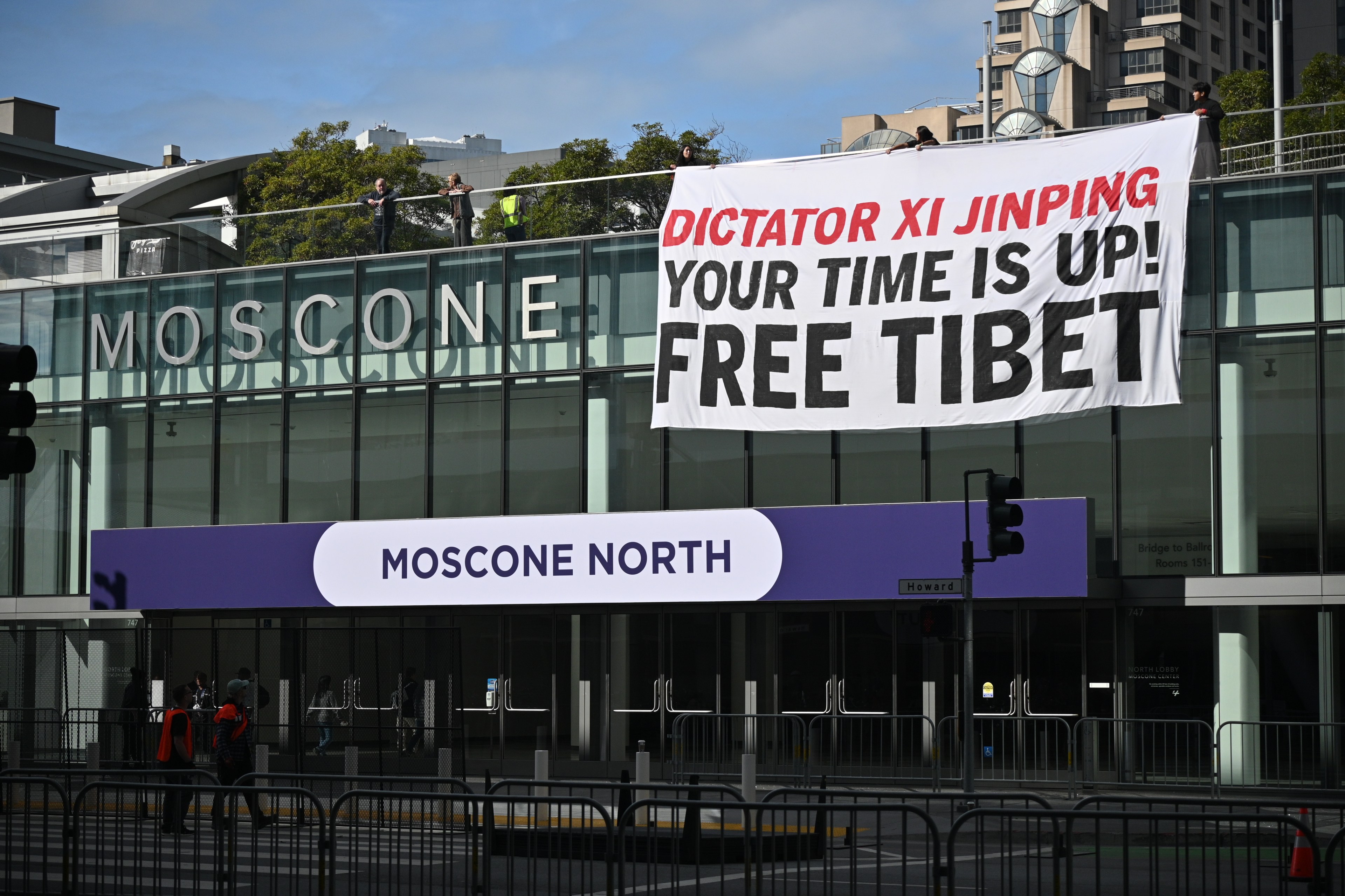 A sign reading "Dictator Xi Jinping Your Time Is Up! Free Tibet" hangs from Moscone Center.