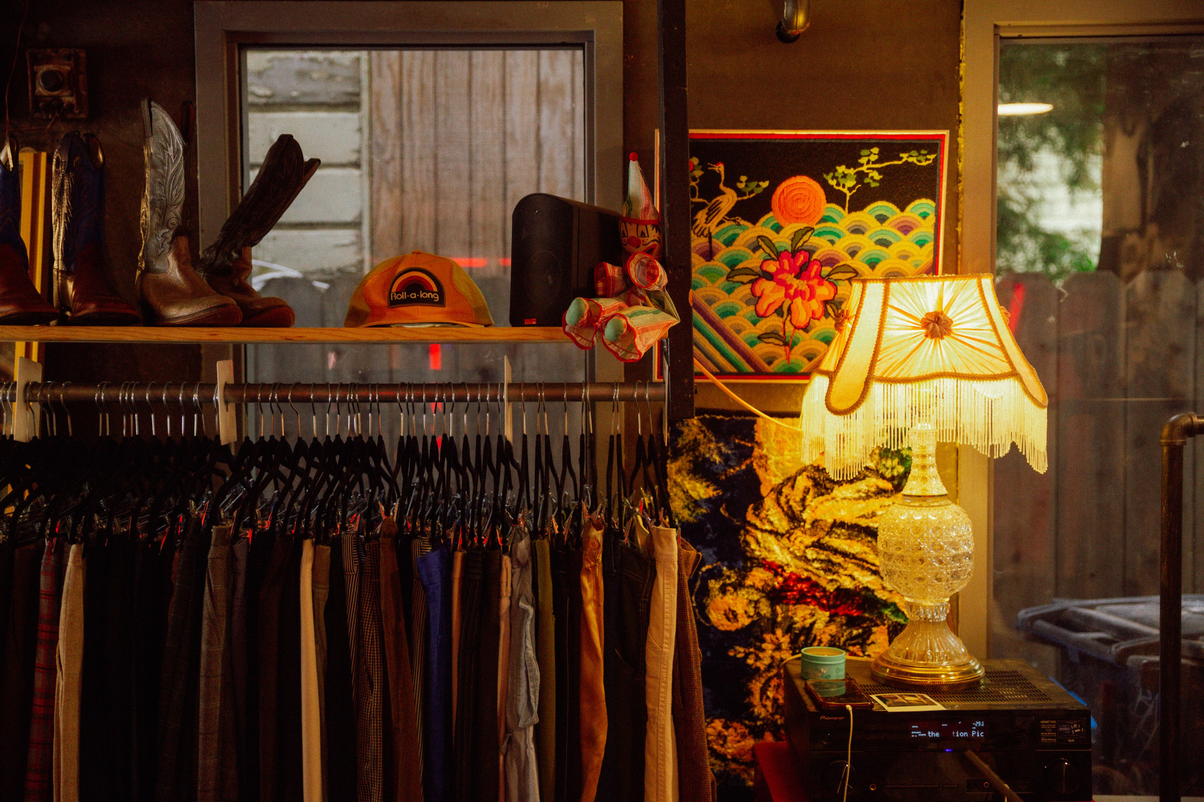 A retro lamp glows next to a rack of vintage clothes inside Sensitive Vintage. 