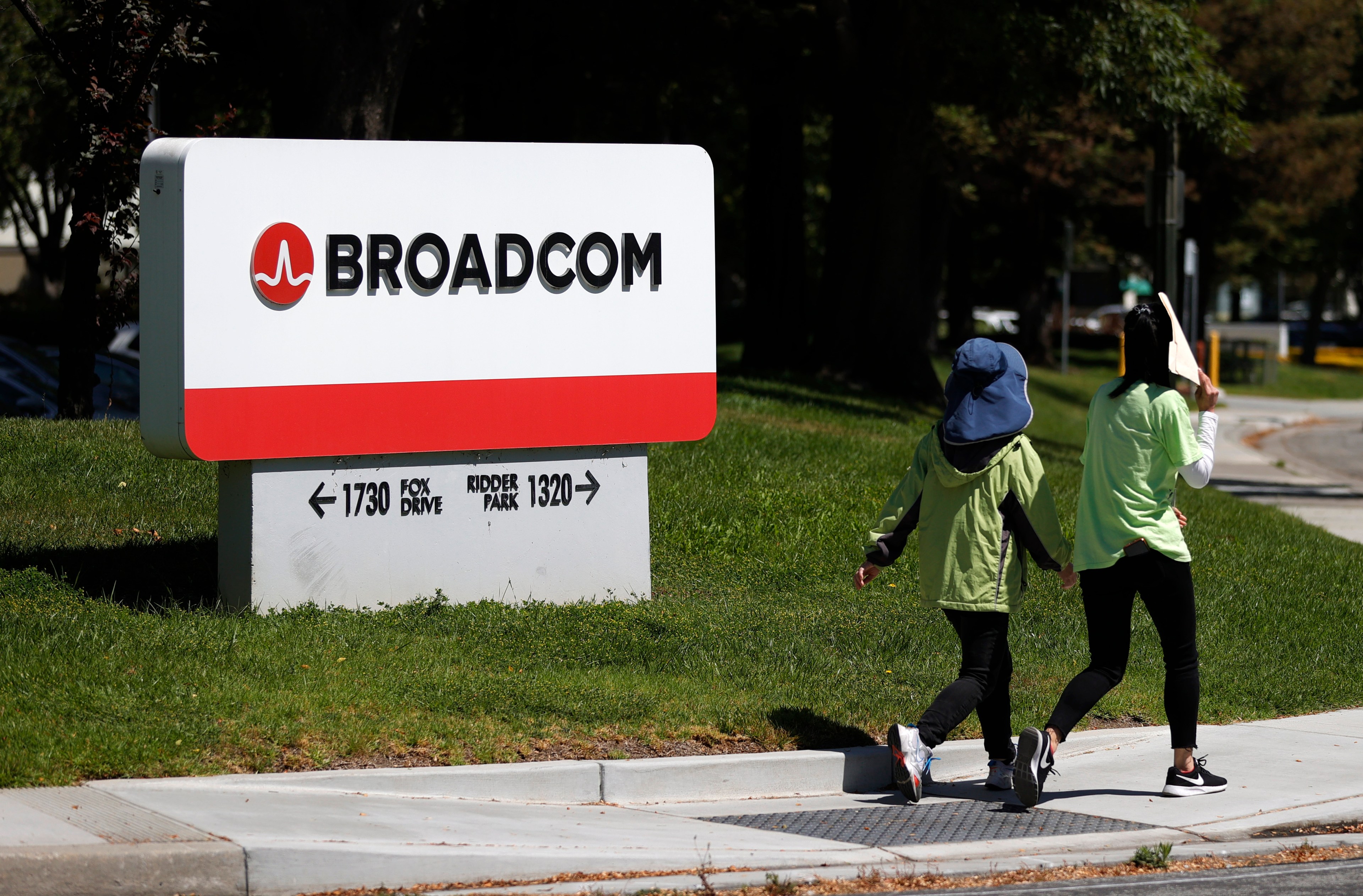 two people walking in front of a sign saying Broadcom.
