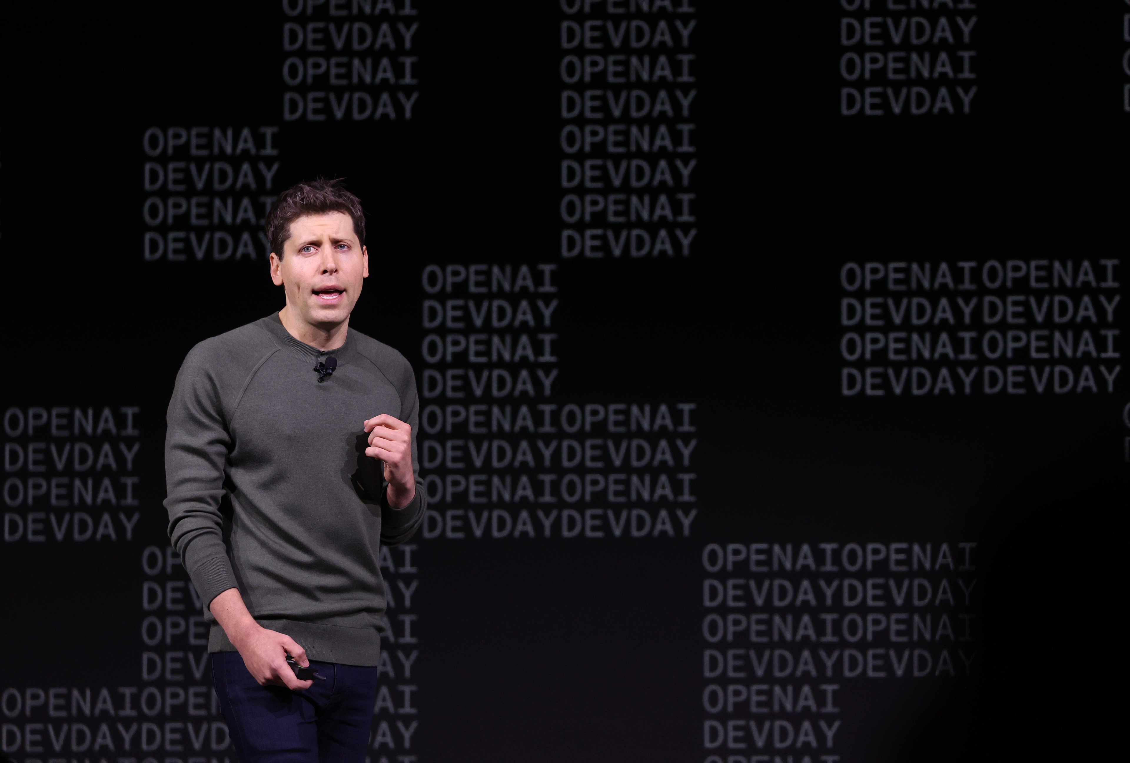 OpenAI CEO Sam Altman, wearing a gray sweater, speaks at OpenAI's DevDay conference in San Francisco