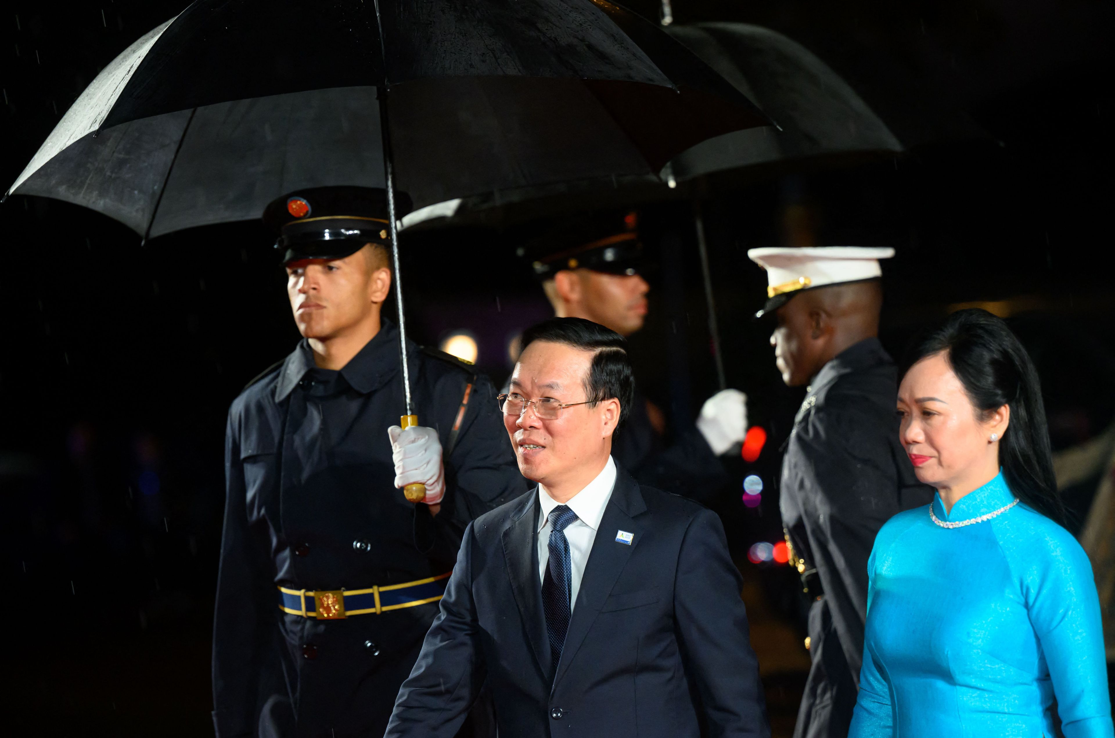 Vietnam's President Vo Van Thuong and his spouse Phan Thi Thanh Tam, dressed in formal wear walks between members of security personnel.