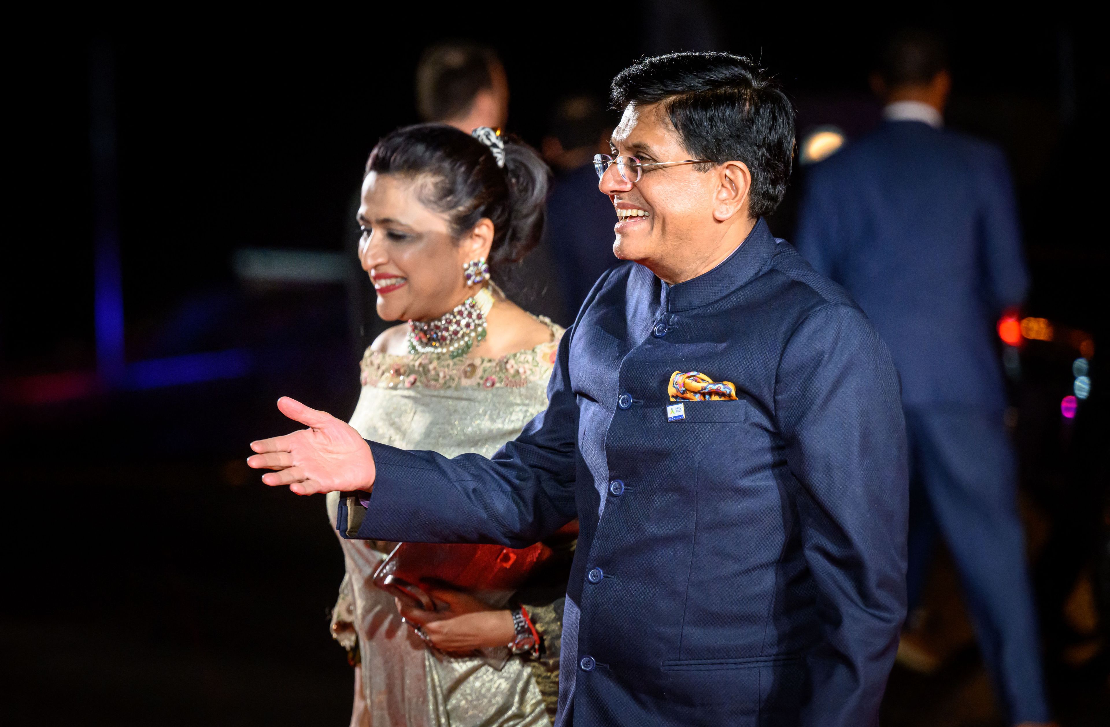 India's Minister of Textiles, Minister of Commerce and Industry Piyush Goyal smiles while extending his hand to greet someone off screen while and his spouse Seema Goyal by his side.